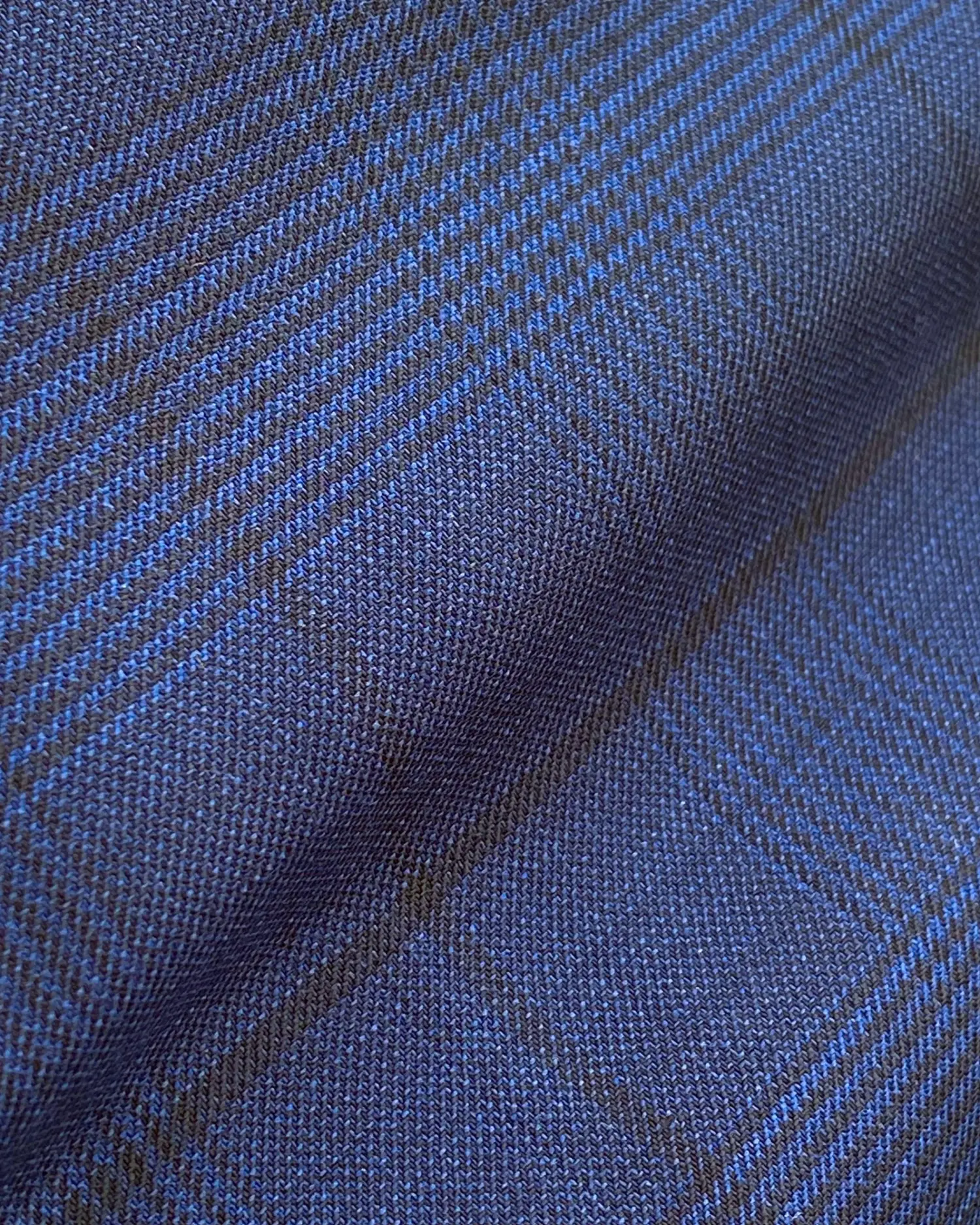 Close-up of blue and dark textured plaid fabric pattern, highlighting detailed weave and intricate design.