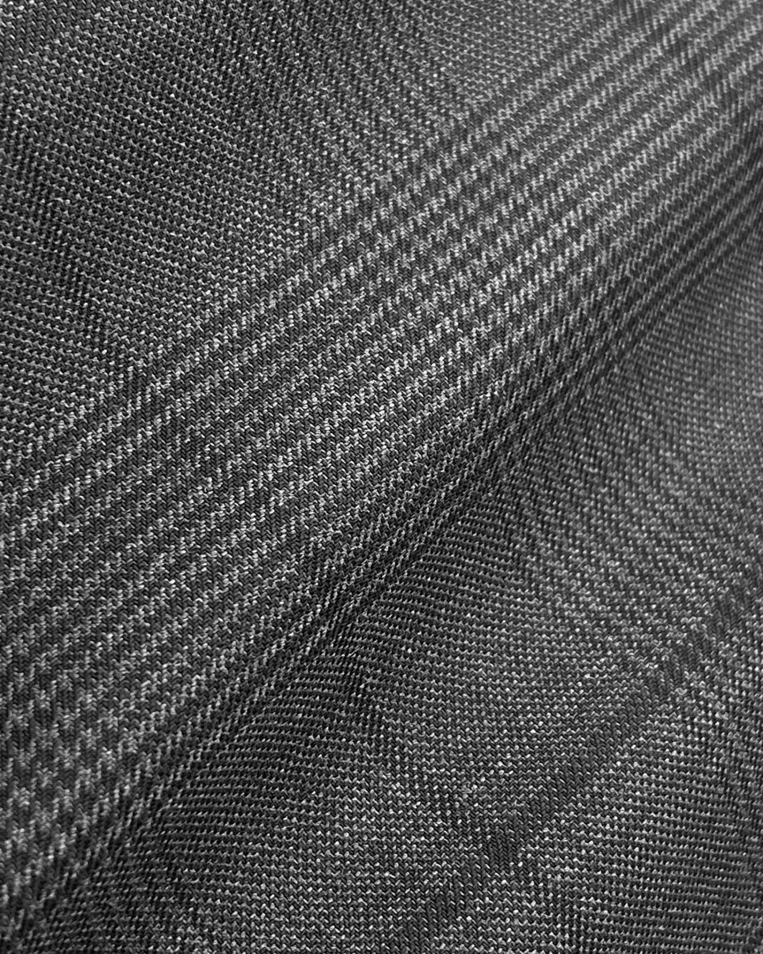 Gray herringbone textured fabric close-up, showcasing intricate pattern detail and woven texture.
