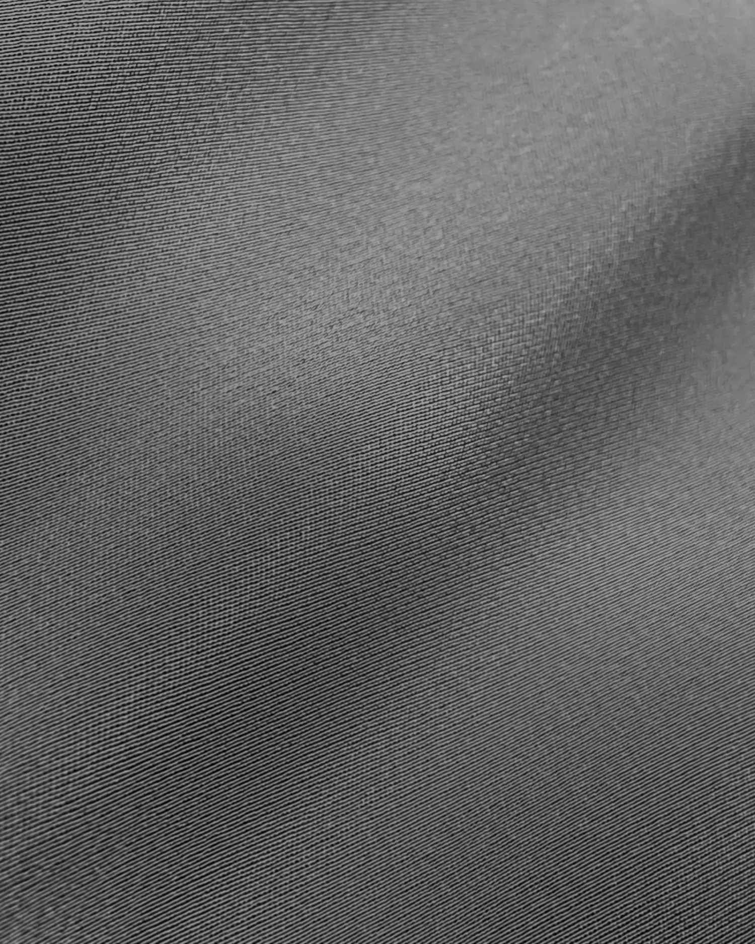 Close-up of smooth gray fabric texture, highlighting fine weave details and soft folds.