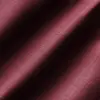 Close-up of maroon textured fabric with diagonal folds, showcasing intricate weave pattern and rich color.