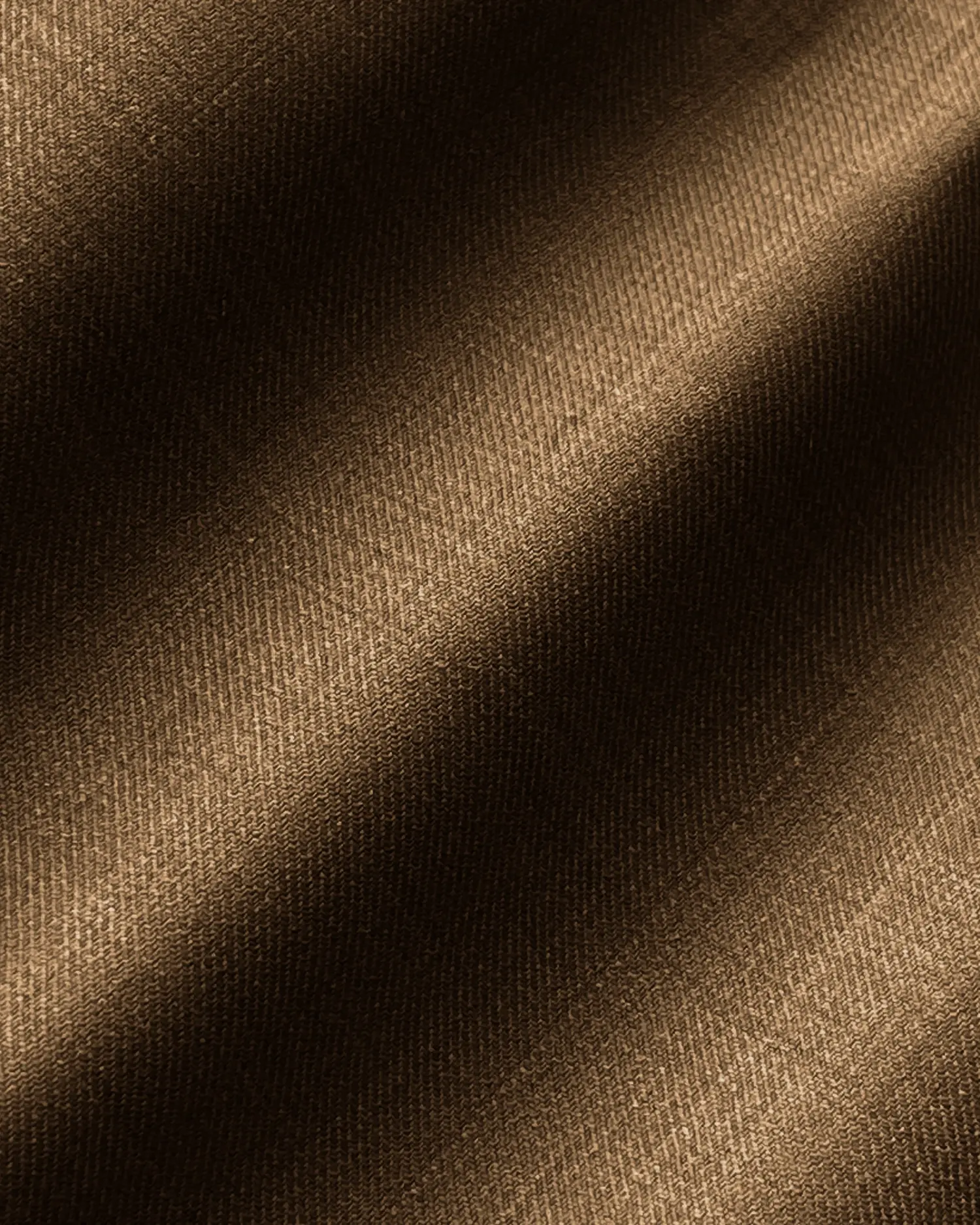 Close-up of luxurious brown fabric texture with soft lighting and diagonal shadows.