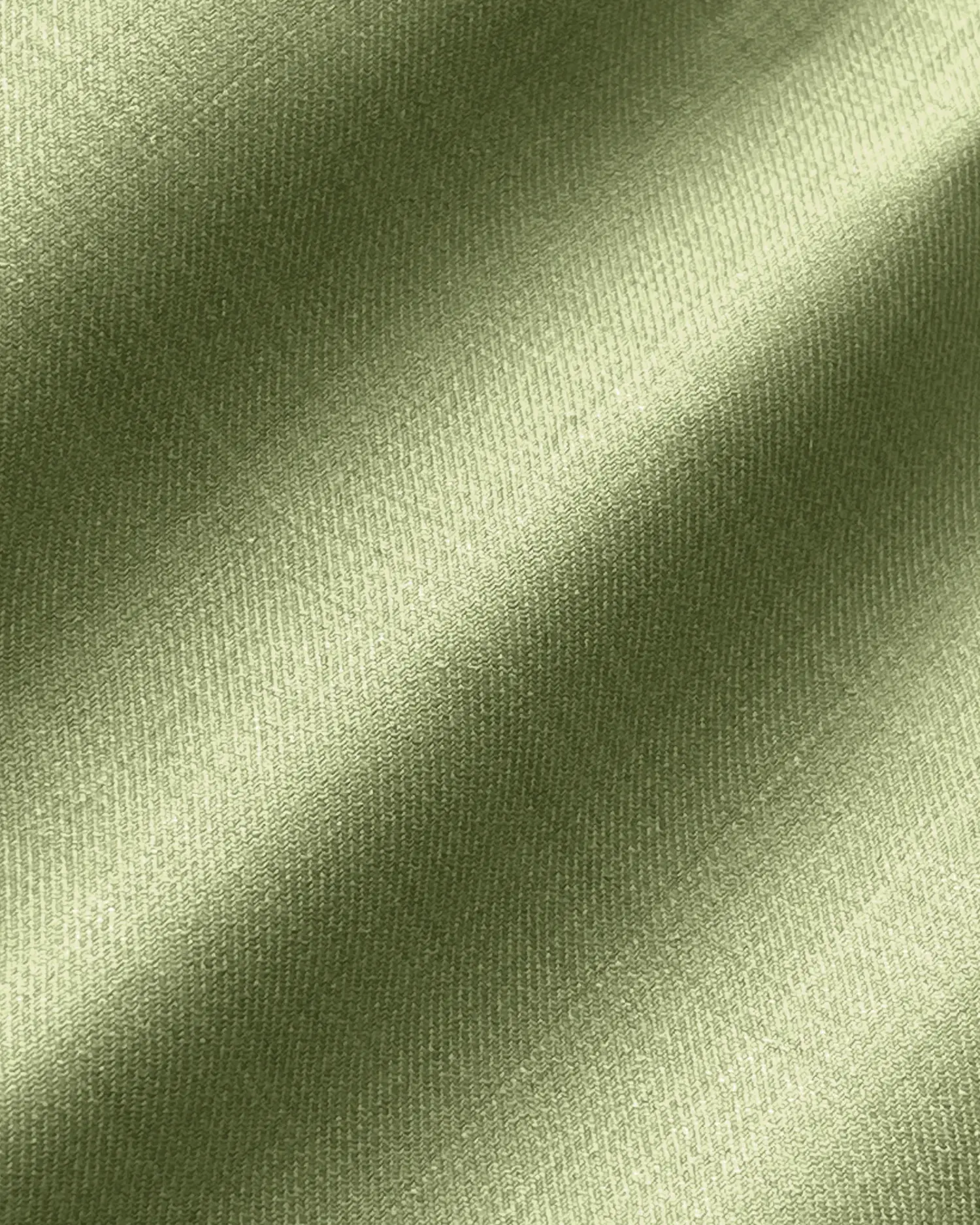 Close-up of smooth, light green satin fabric with a subtle sheen and diagonal folds.