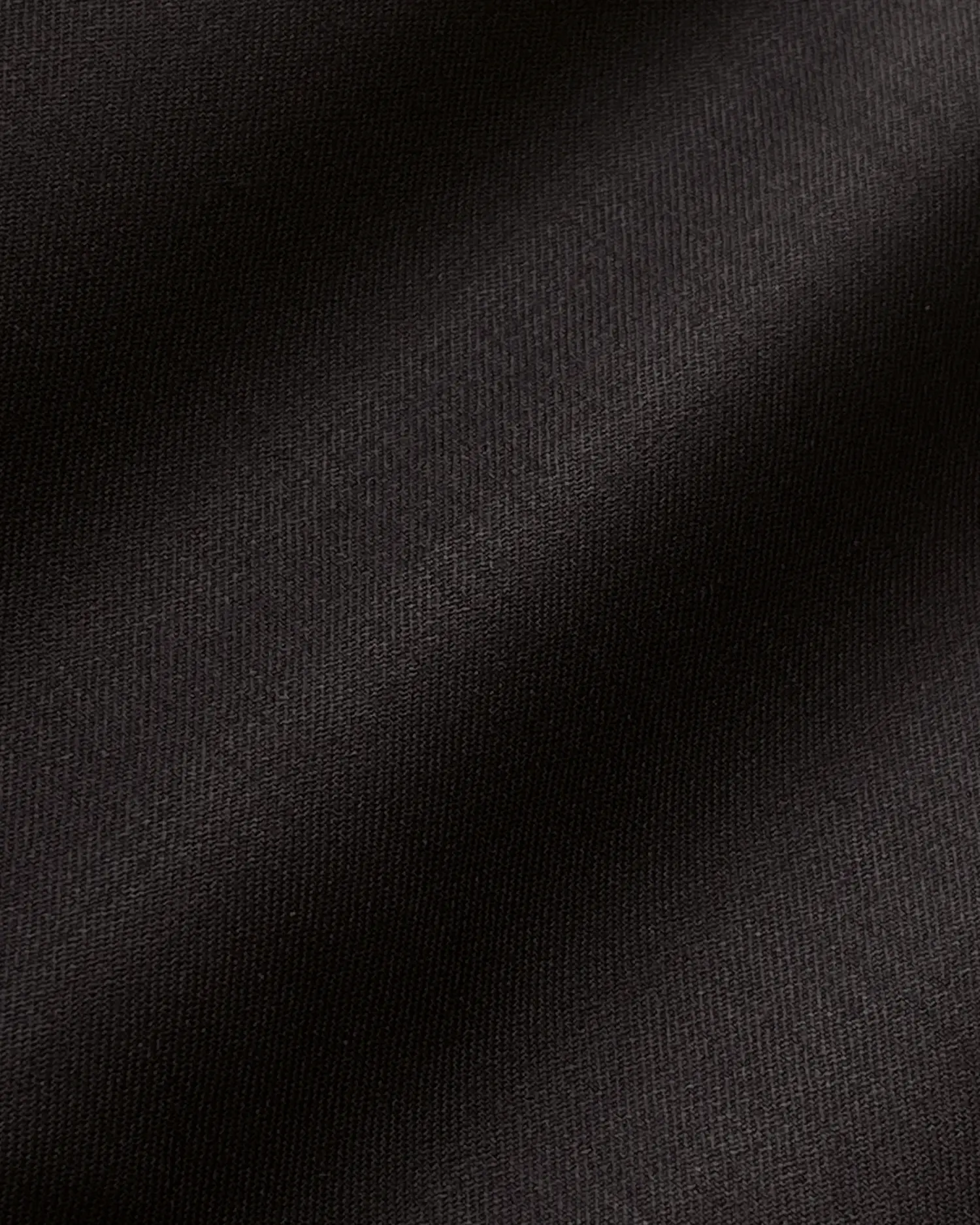 Close-up of smooth black fabric texture with soft shadows and light reflections.