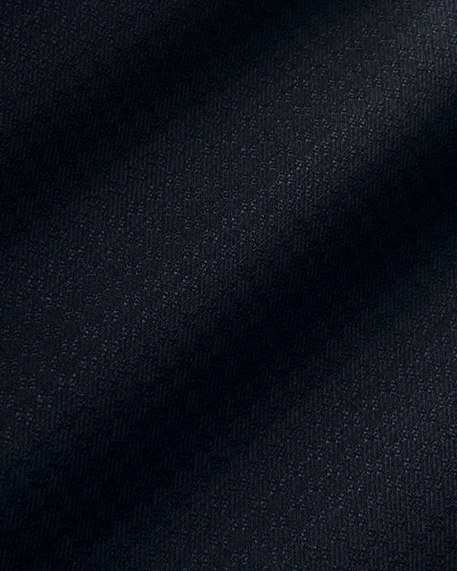 Smooth, dark textured fabric background with subtle light and shadow pattern.