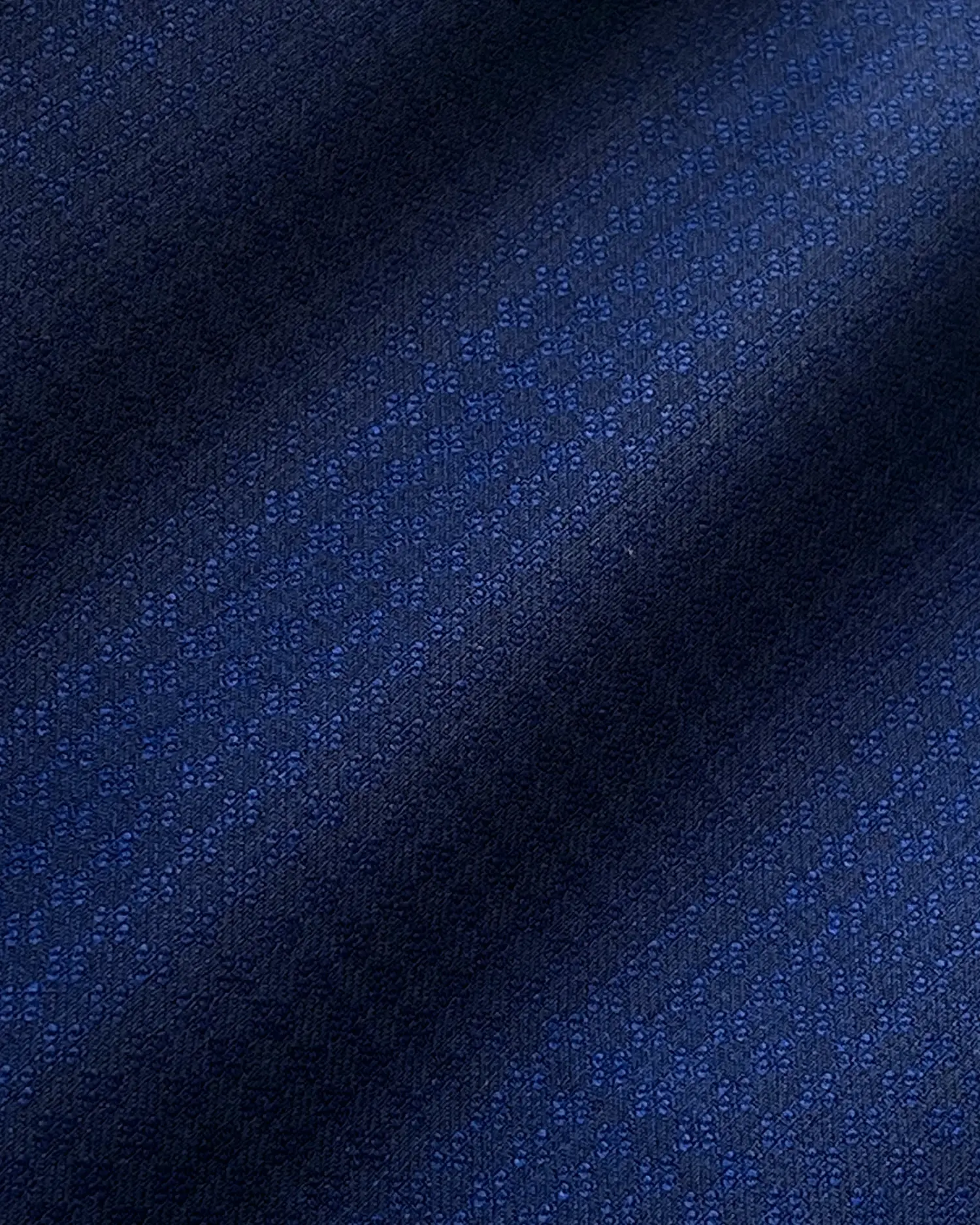 Close-up of dark blue textured fabric with a subtle floral pattern, ideal for upscale fashion or upholstery applications.
