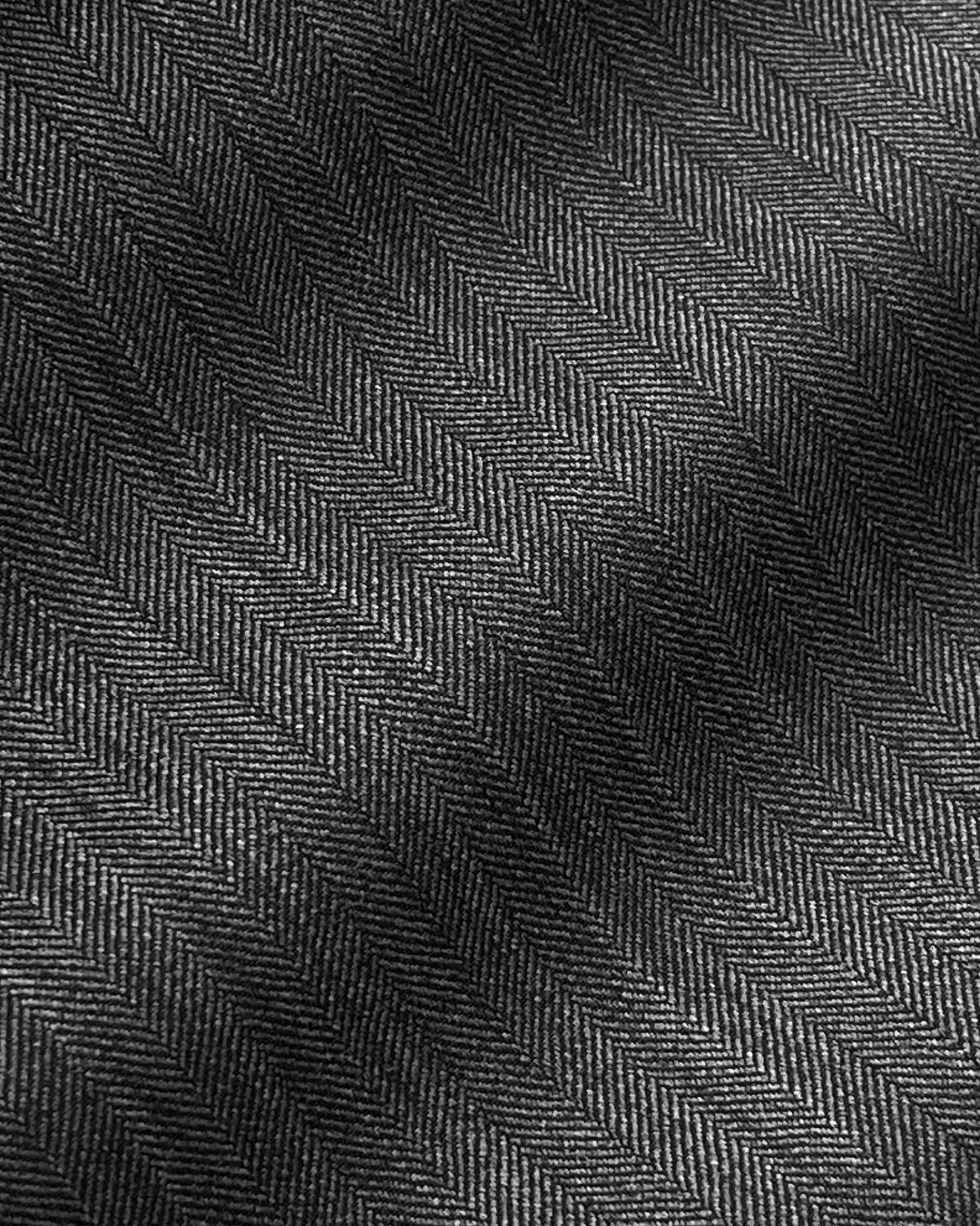Close-up of gray herringbone fabric with diagonal zigzag pattern and light shadow effect.