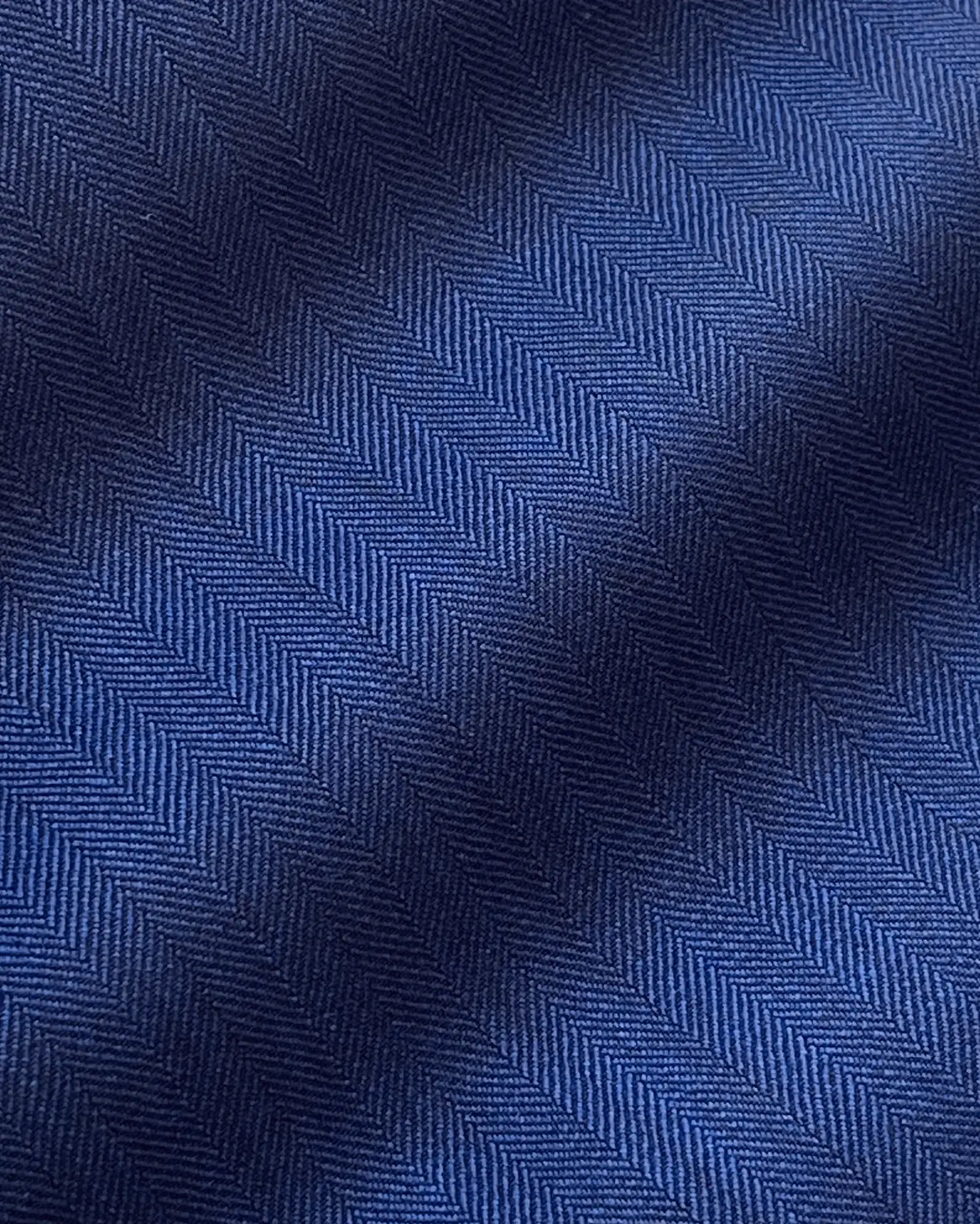 Close-up of blue herringbone fabric texture with diagonal zigzag pattern.
