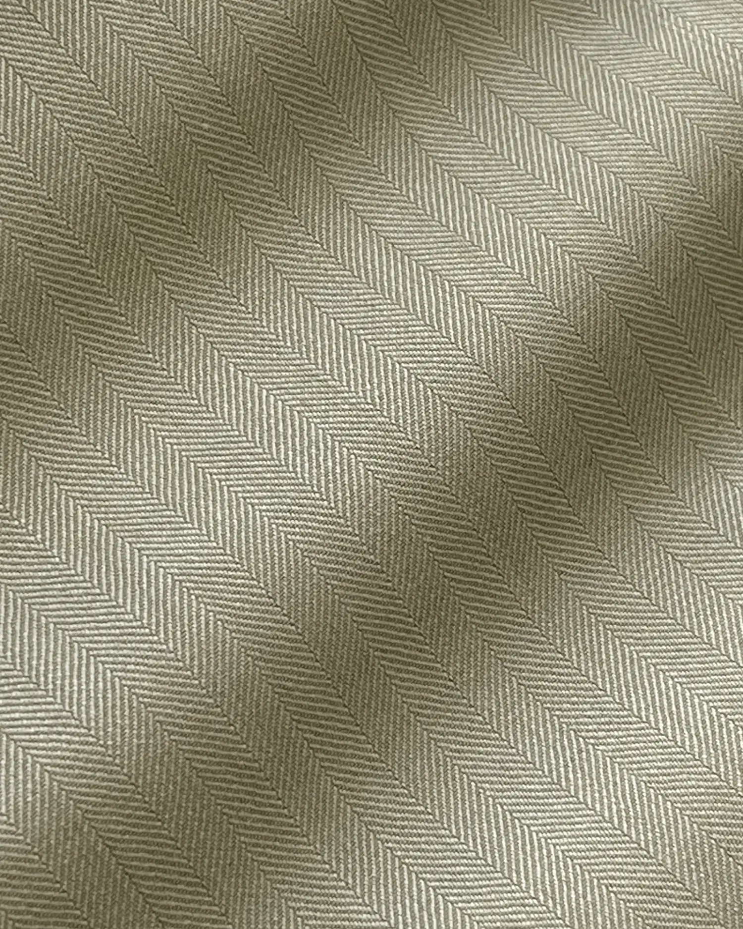 Close-up of beige herringbone woven fabric texture with zigzag pattern for upholstery and interior design.