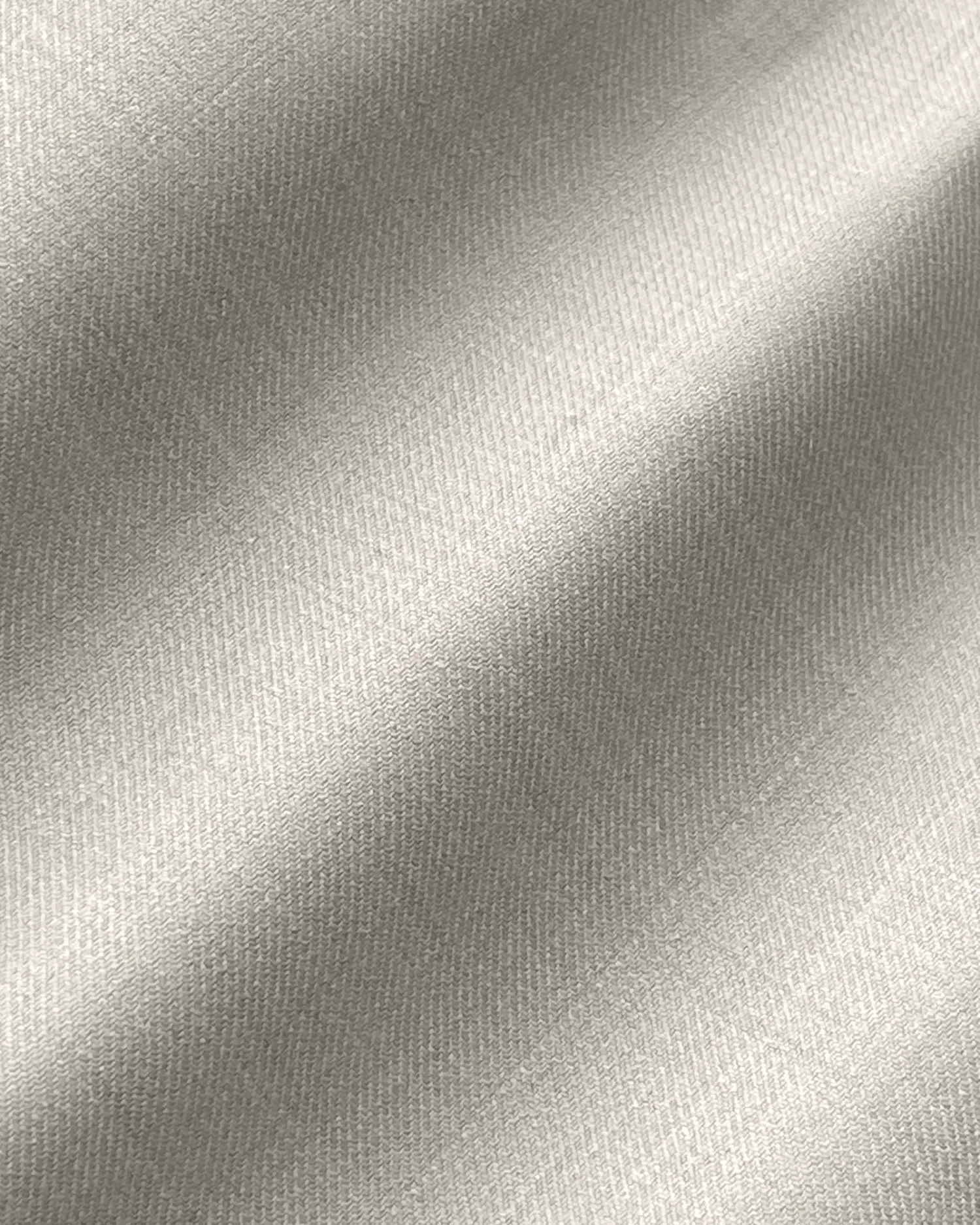 Close-up of beige fabric texture with a diagonal pattern, showcasing smooth and elegant woven details.