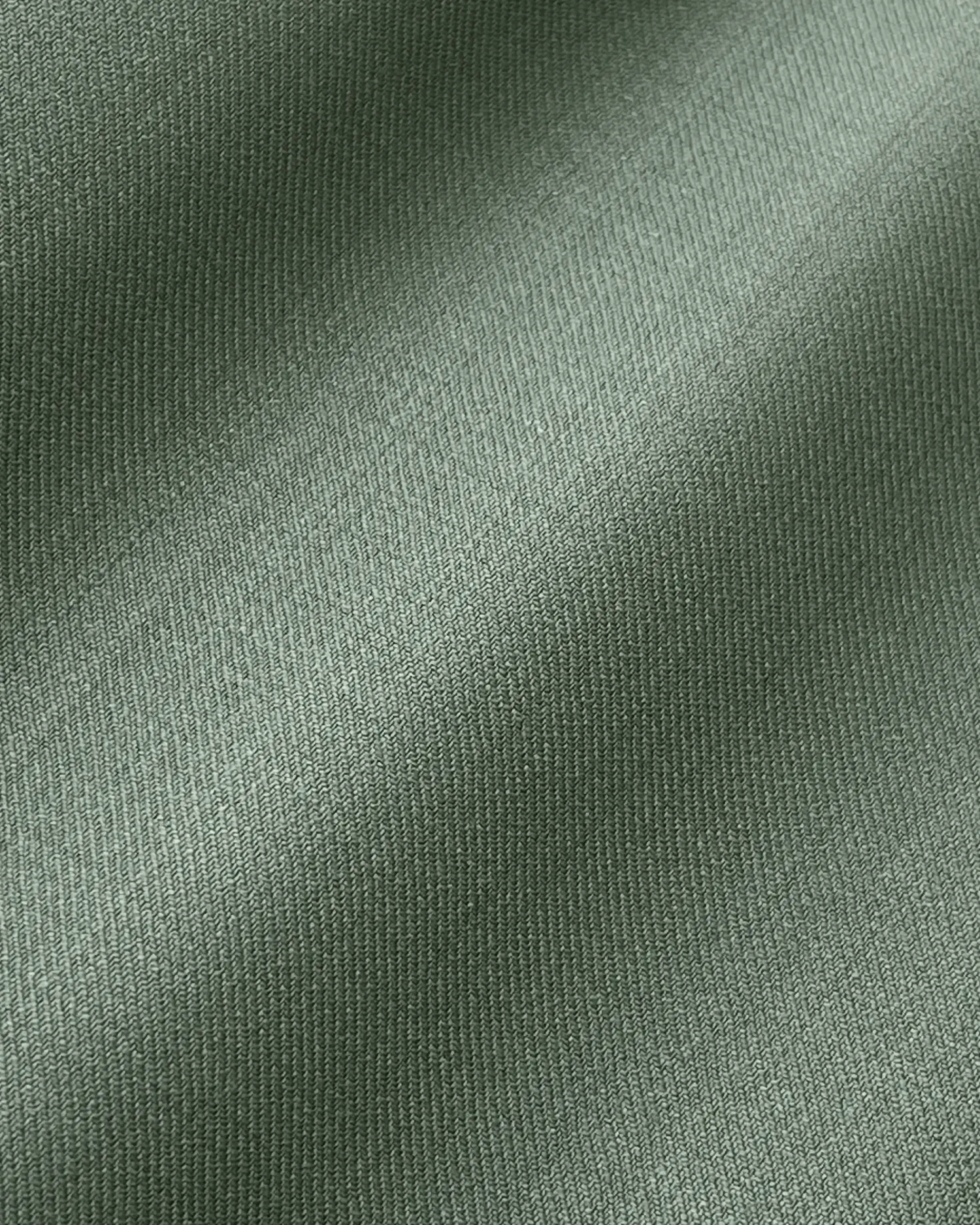Close-up of green textured fabric with a subtle sheen, highlighting its intricate weave pattern.