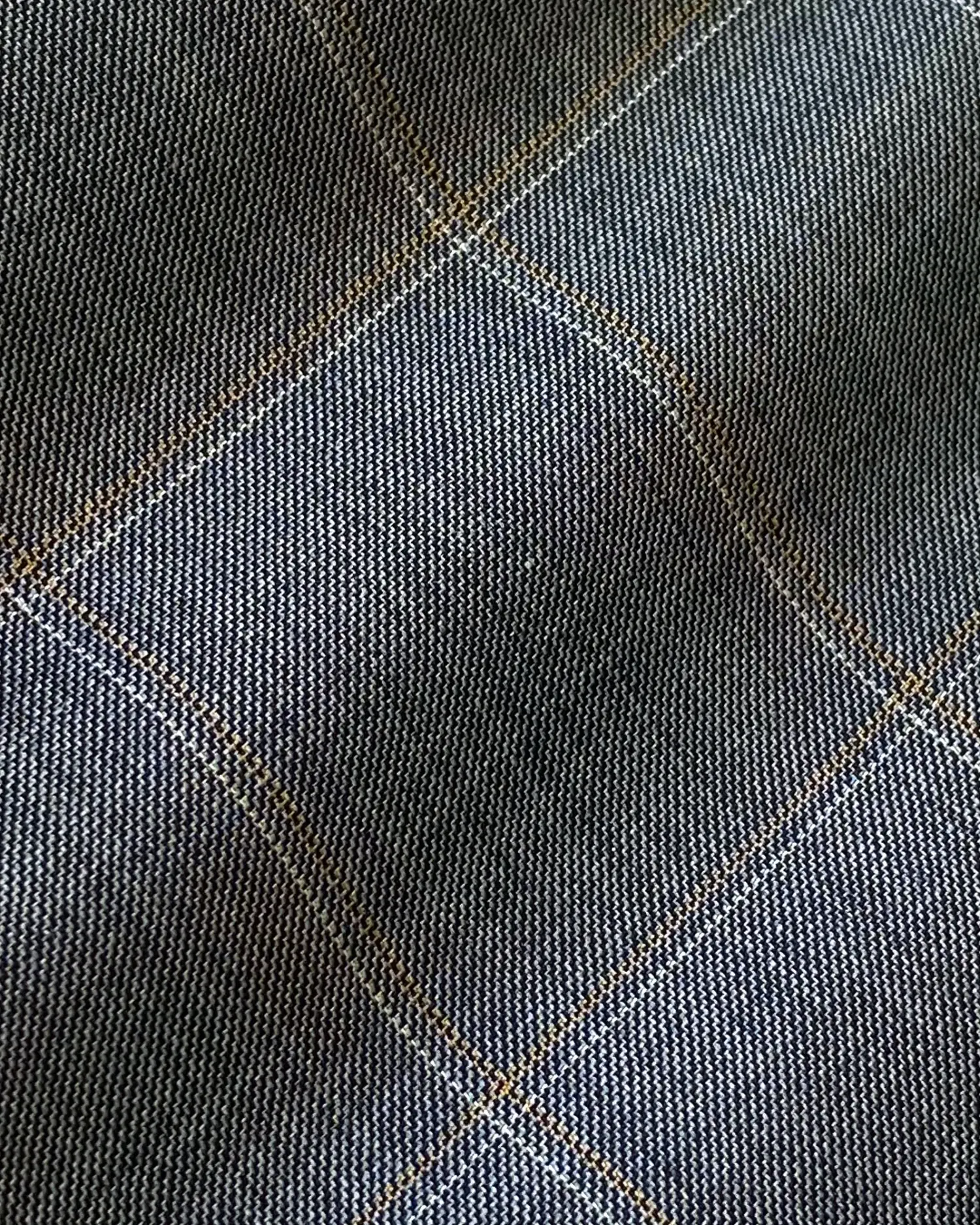 Close-up view of blue tweed fabric with beige grid pattern, ideal for clothing and upholstery design.