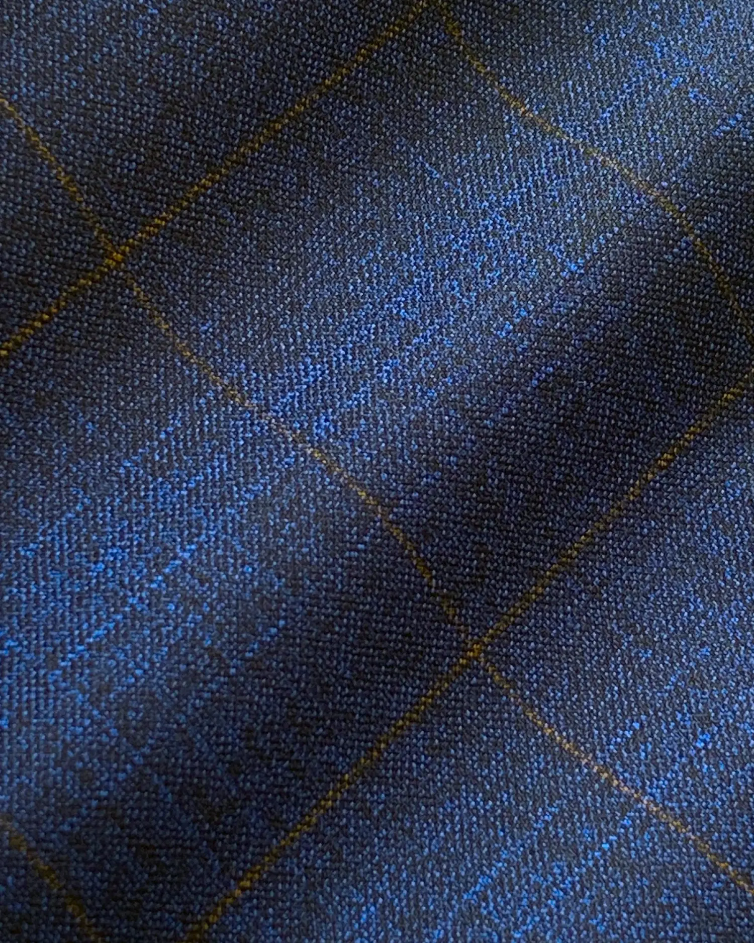 Close-up of dark blue plaid fabric with textured pattern and intersecting gold lines.