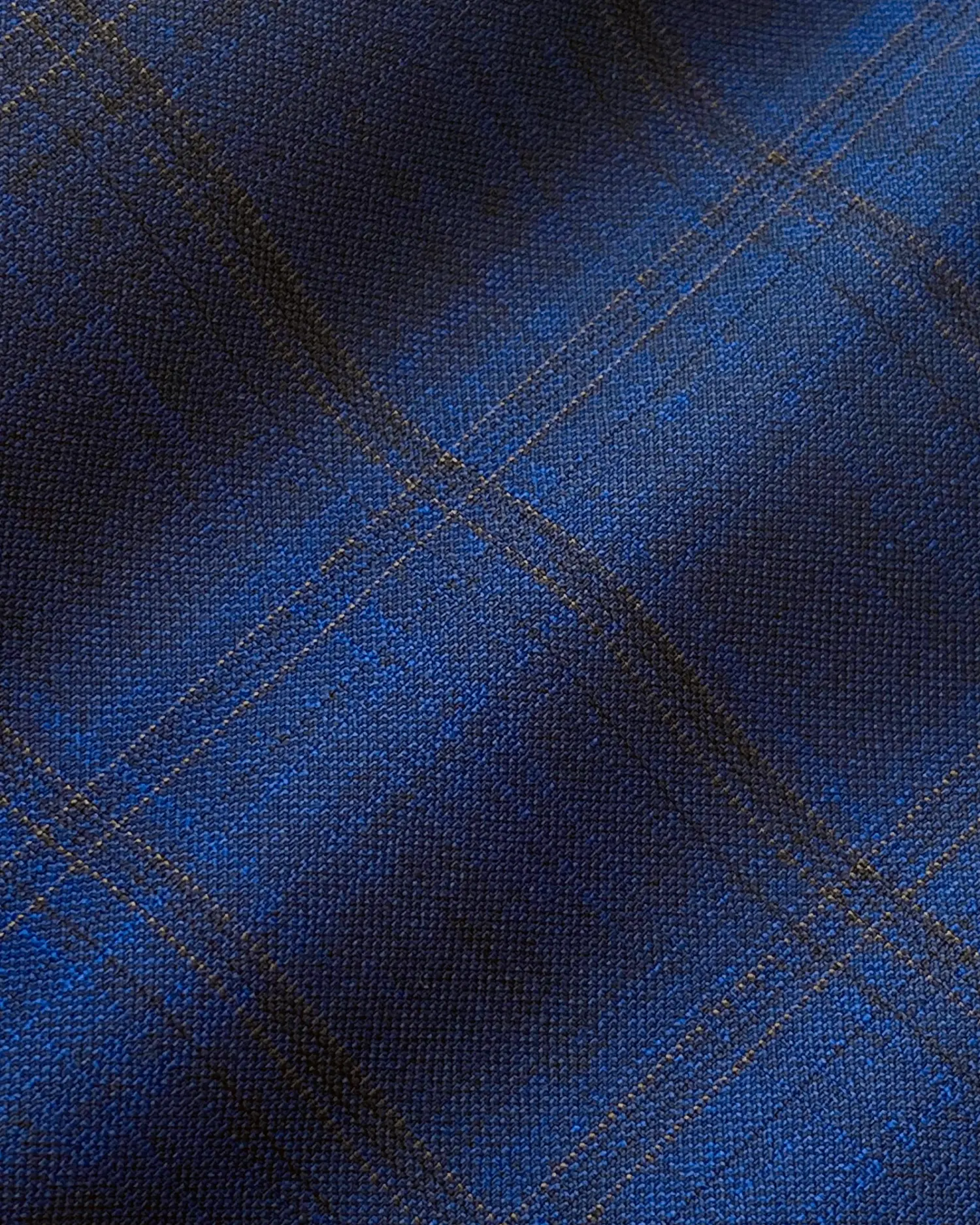 Close-up of blue plaid fabric with intersecting lines, showcasing a textured pattern ideal for fashion or upholstery design.