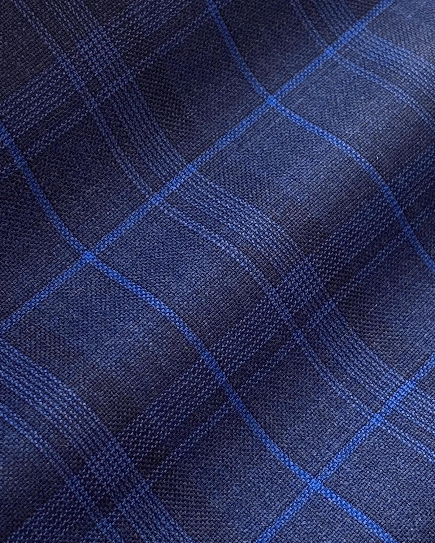 Blue plaid fabric with a classic checkered pattern, perfect for clothing or upholstery design.