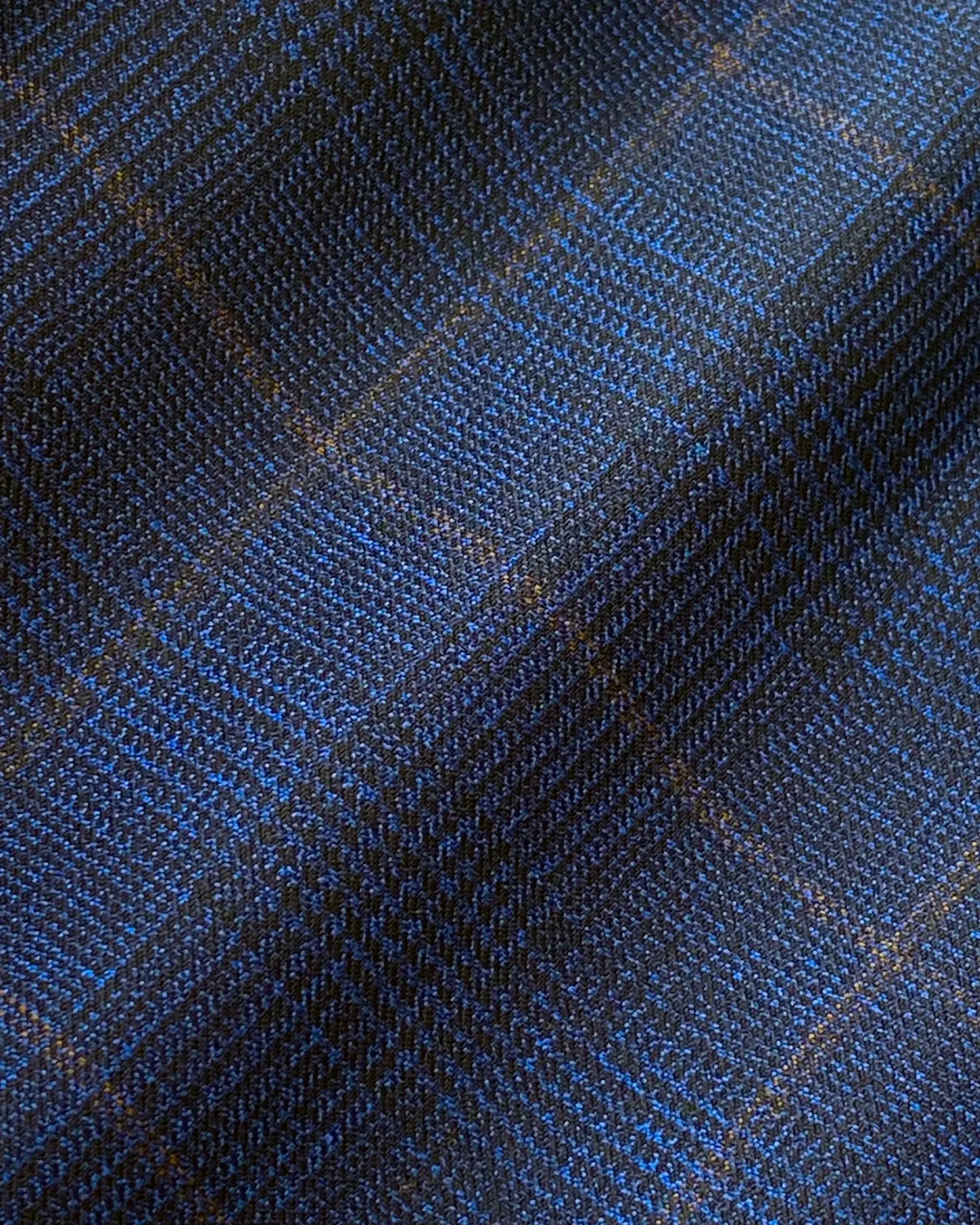 Close-up of blue and black plaid fabric with intricate patterns and textures.