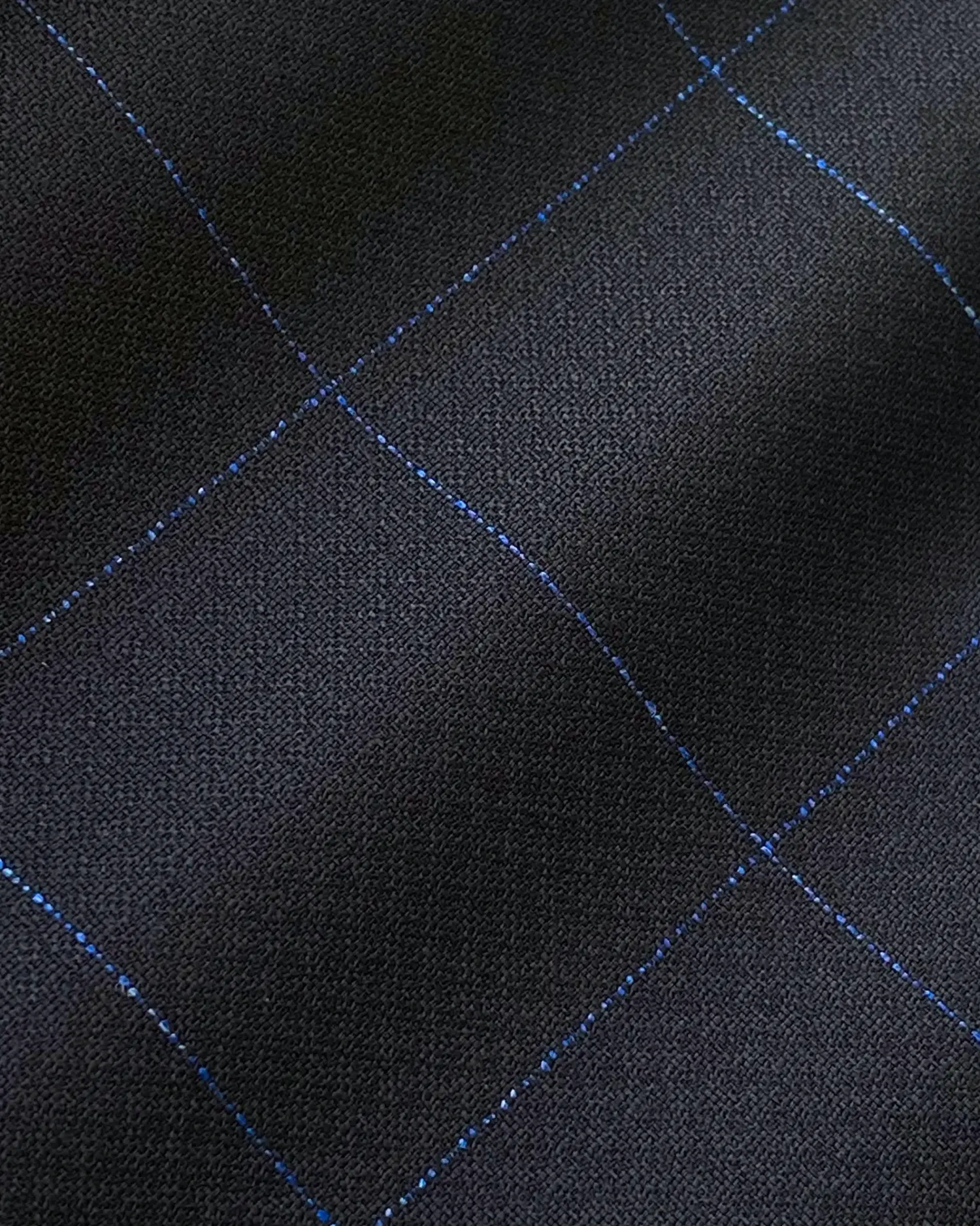 Close-up of black fabric with blue grid pattern, showing texture and stitching detail. Ideal for fashion or design themes.