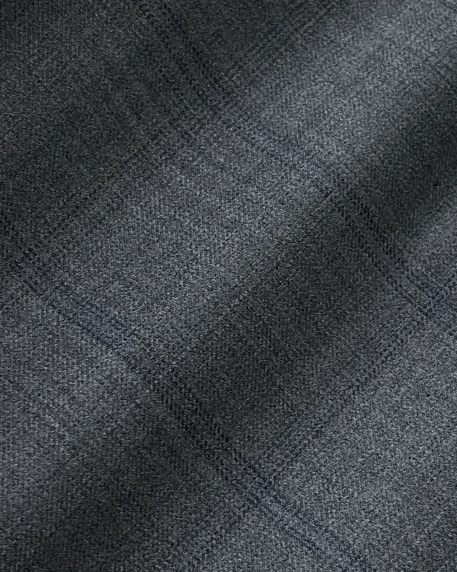 Close-up of gray plaid textured fabric with subtle lines and soft shadows.