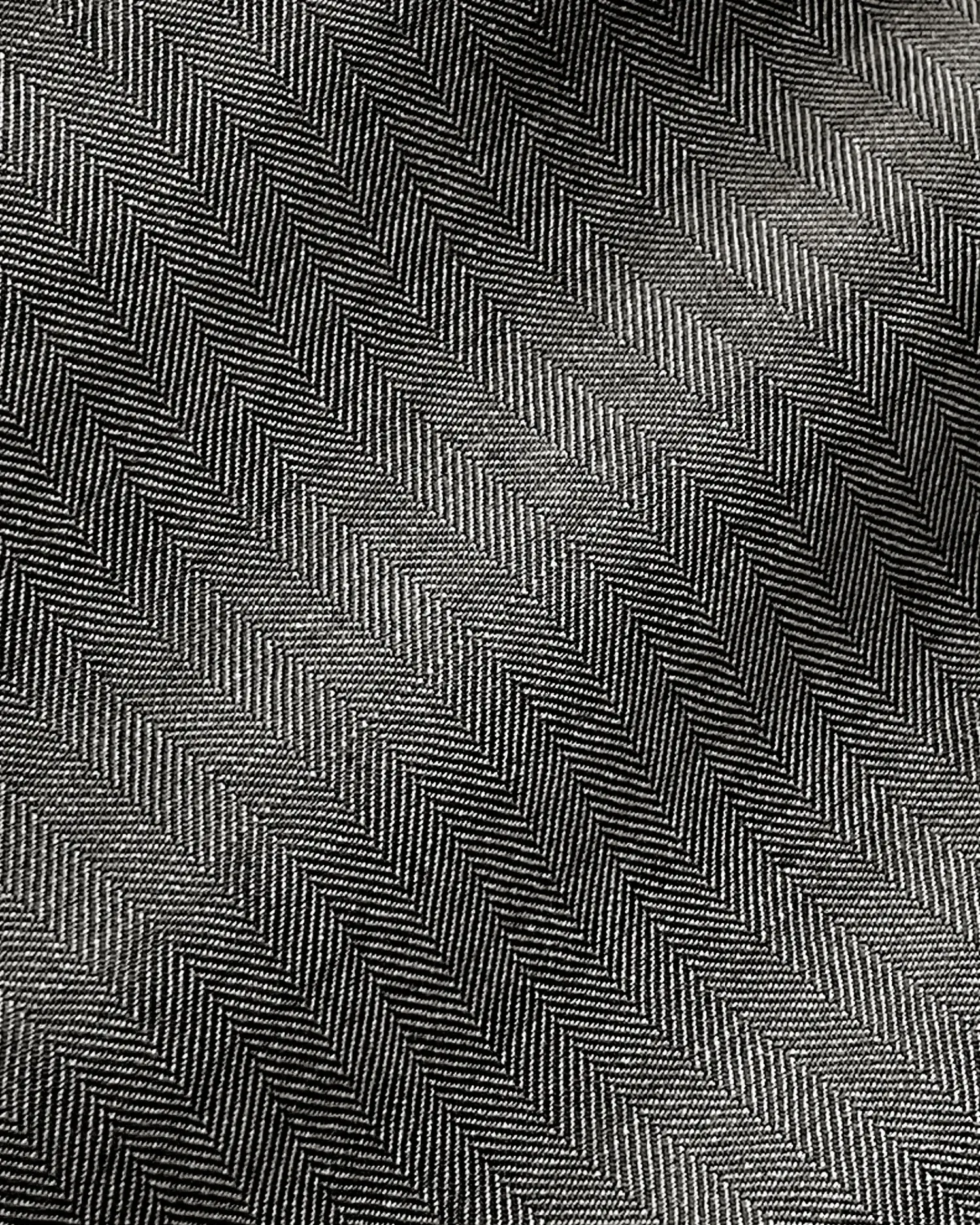 Close-up of herringbone pattern fabric with diagonal lines in black and white, showcasing texture and design.