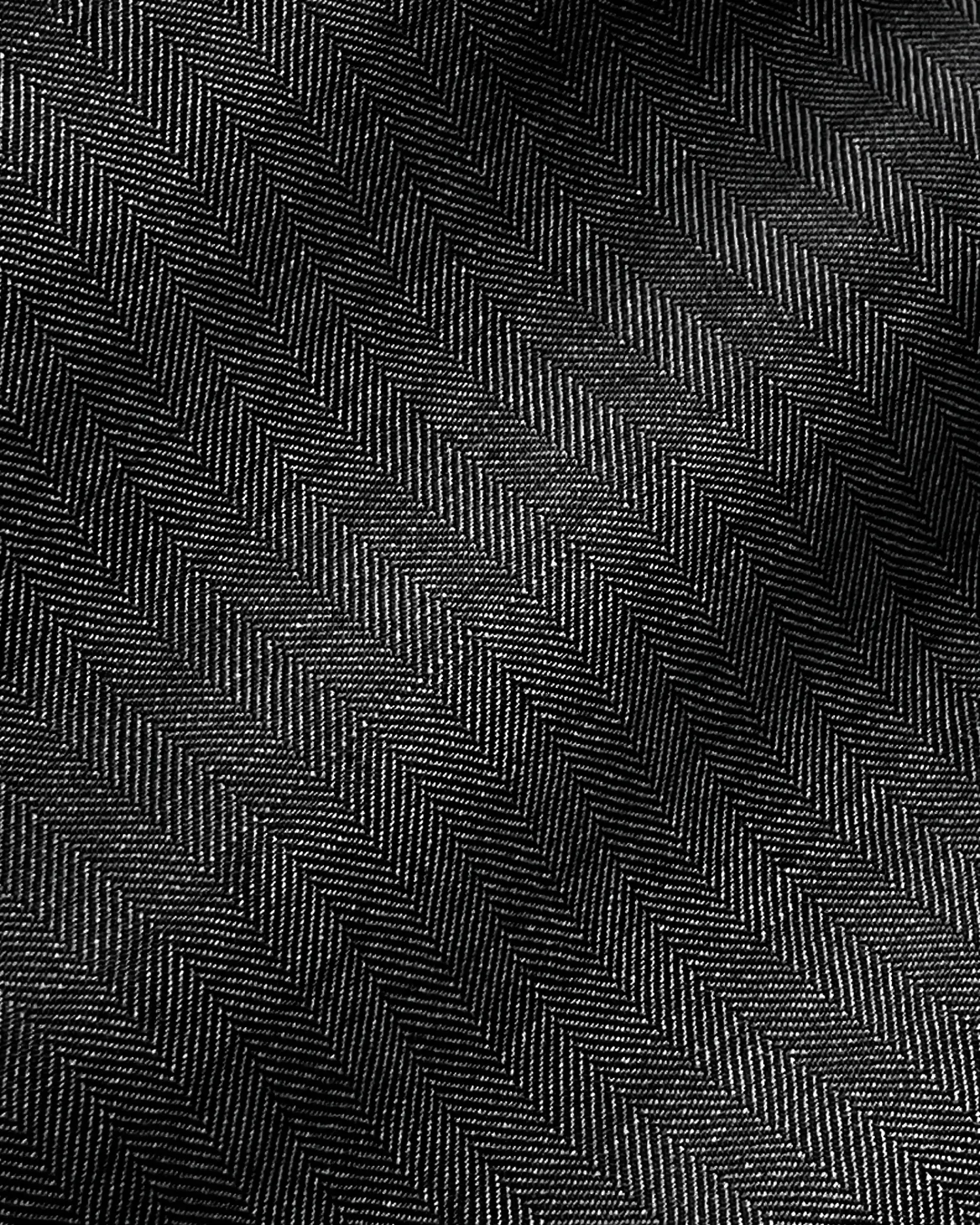 Close-up of dark herringbone fabric texture with detailed zigzag pattern, highlighting textile design and style.
