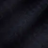 Close-up of dark herringbone fabric texture showing detailed zigzag pattern.