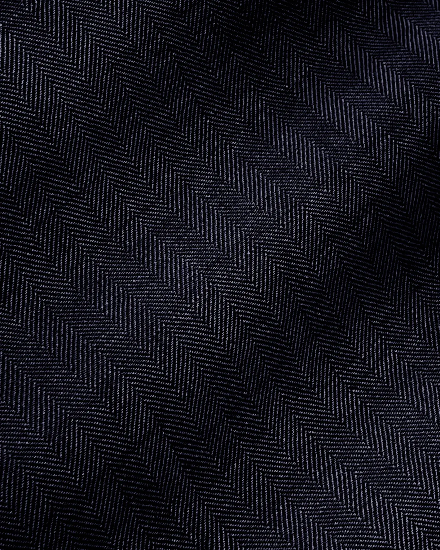 Close-up of dark herringbone fabric texture showing detailed zigzag pattern.