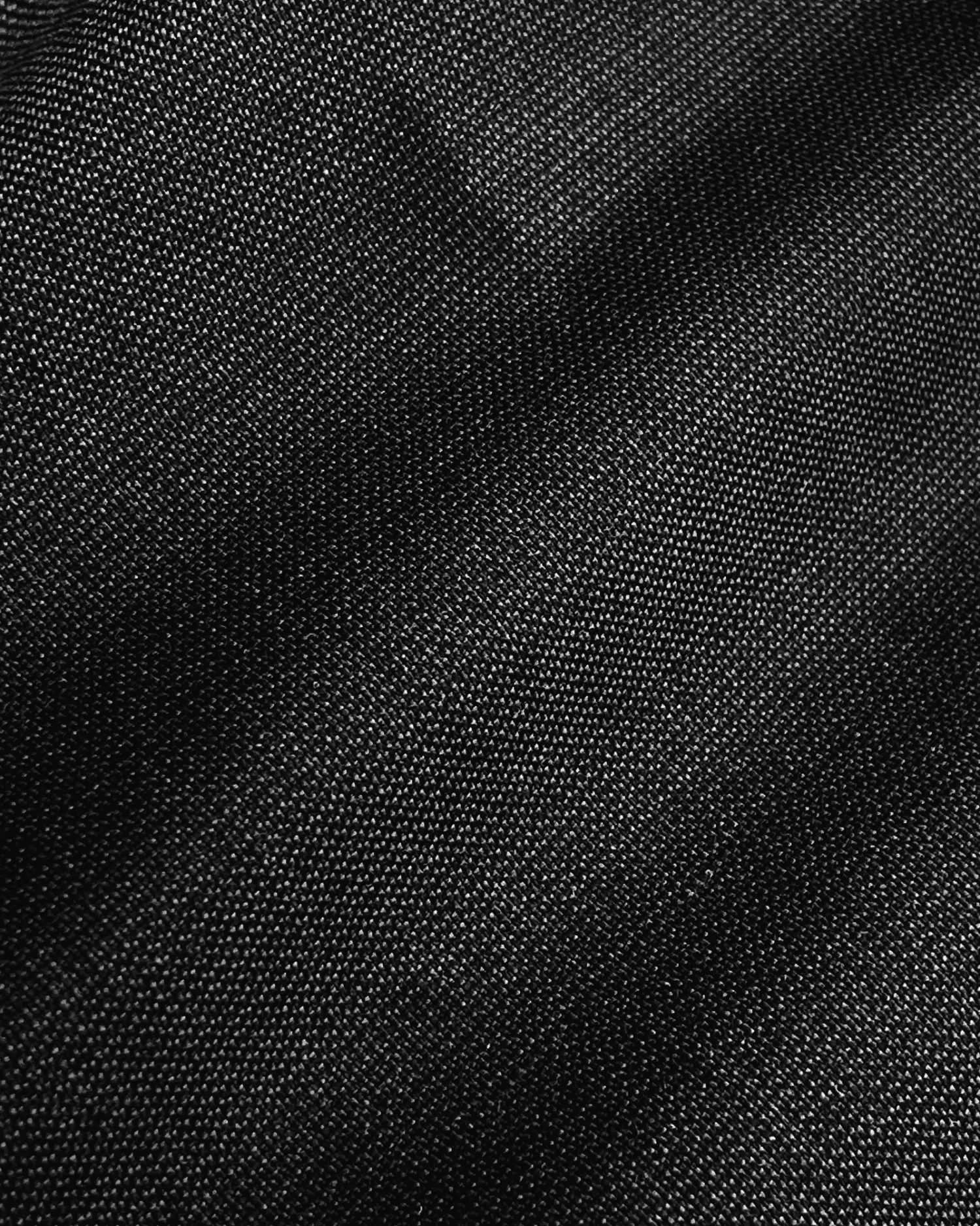 Close-up of textured black fabric with visible weave pattern, suitable for clothing or upholstery.
