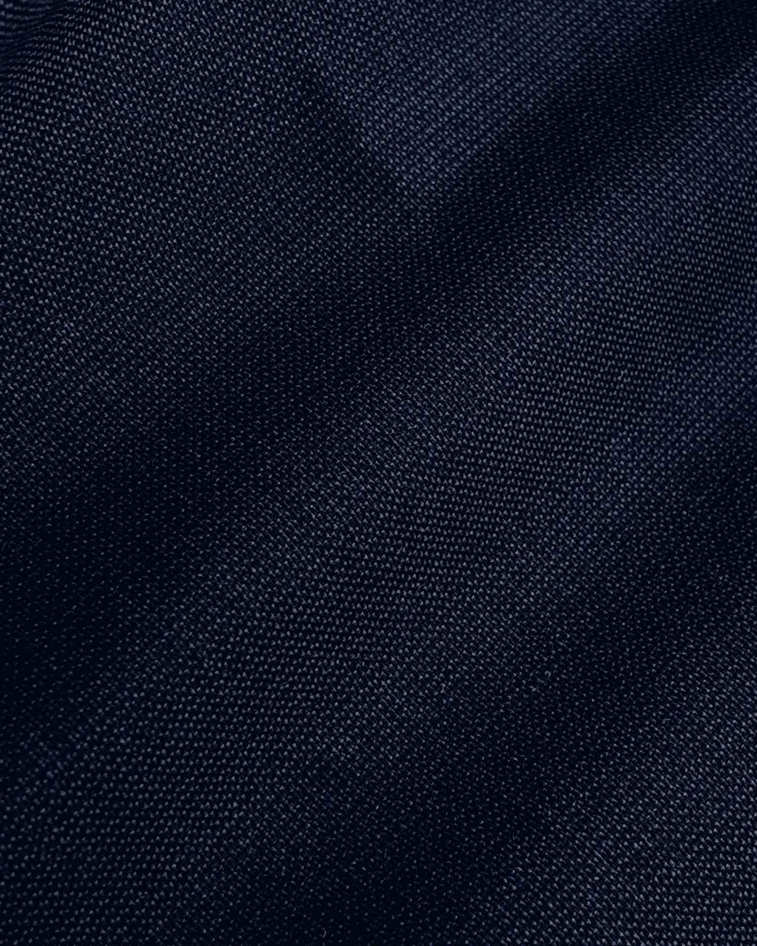 Close-up of dark blue denim fabric texture, showcasing weave pattern and color variations.