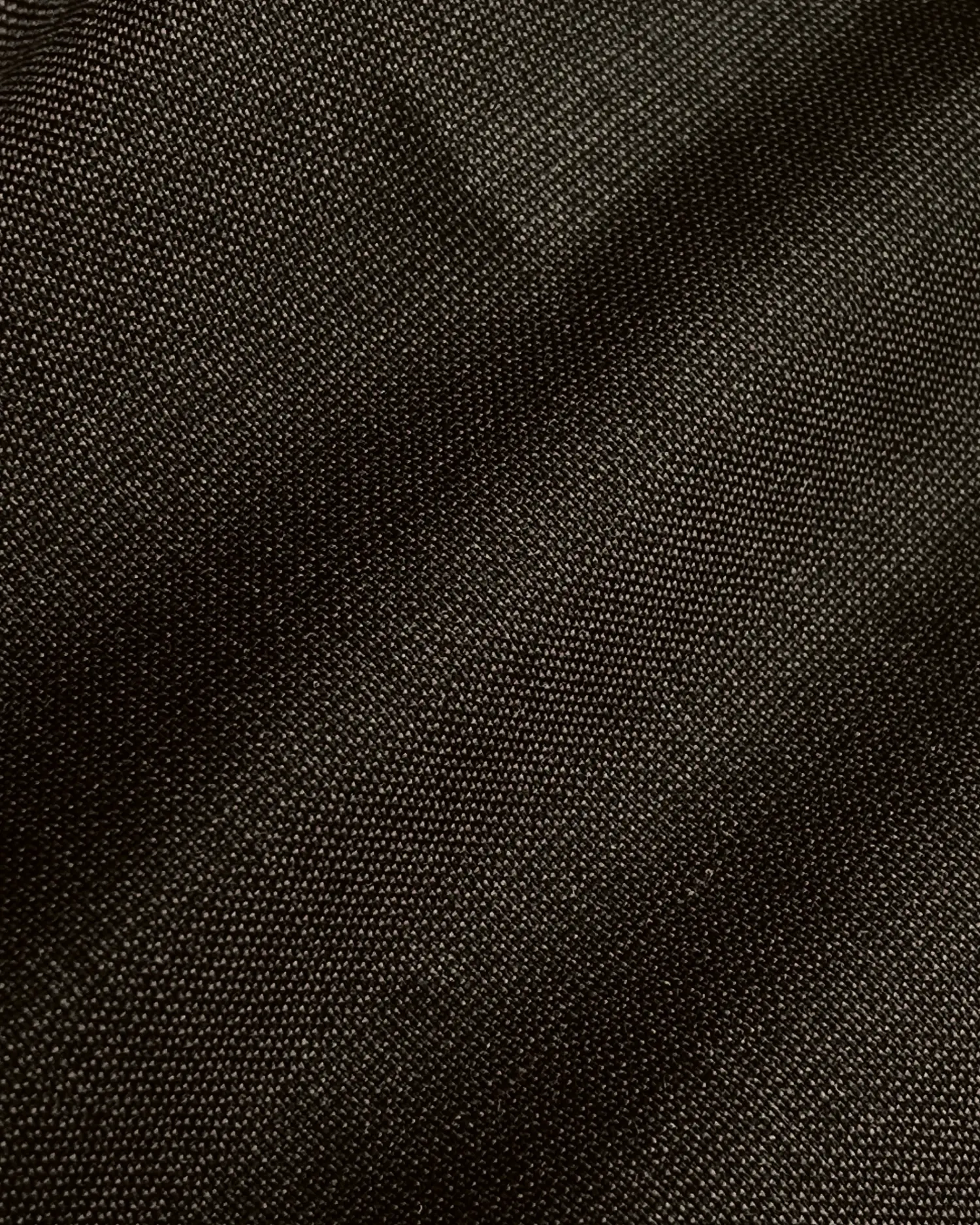 Close-up of dark woven fabric texture, showing detailed cross-thread pattern and subtle sheen.