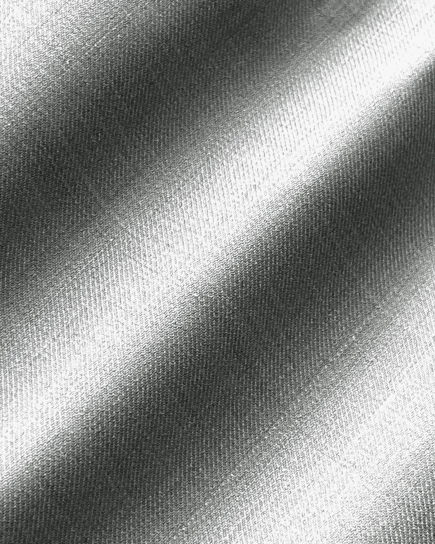 Close-up of metallic fabric texture with diagonal light reflections, showcasing a smooth, shiny surface pattern.