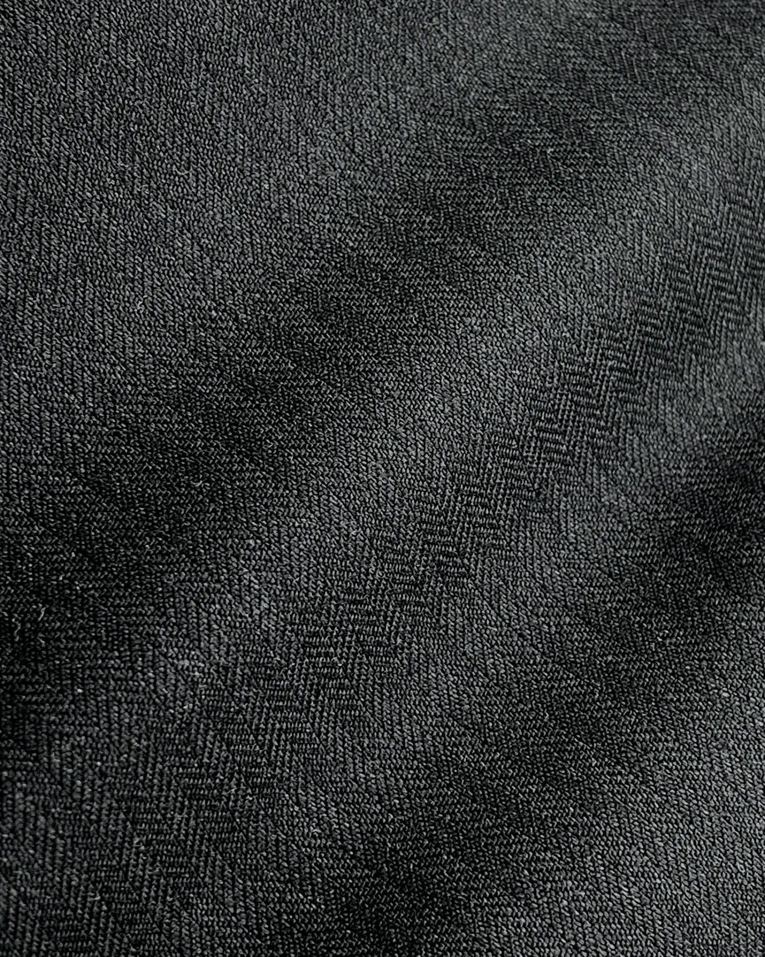 Close-up of black herringbone fabric texture with diagonal pattern, highlighting detailed textile surface design.