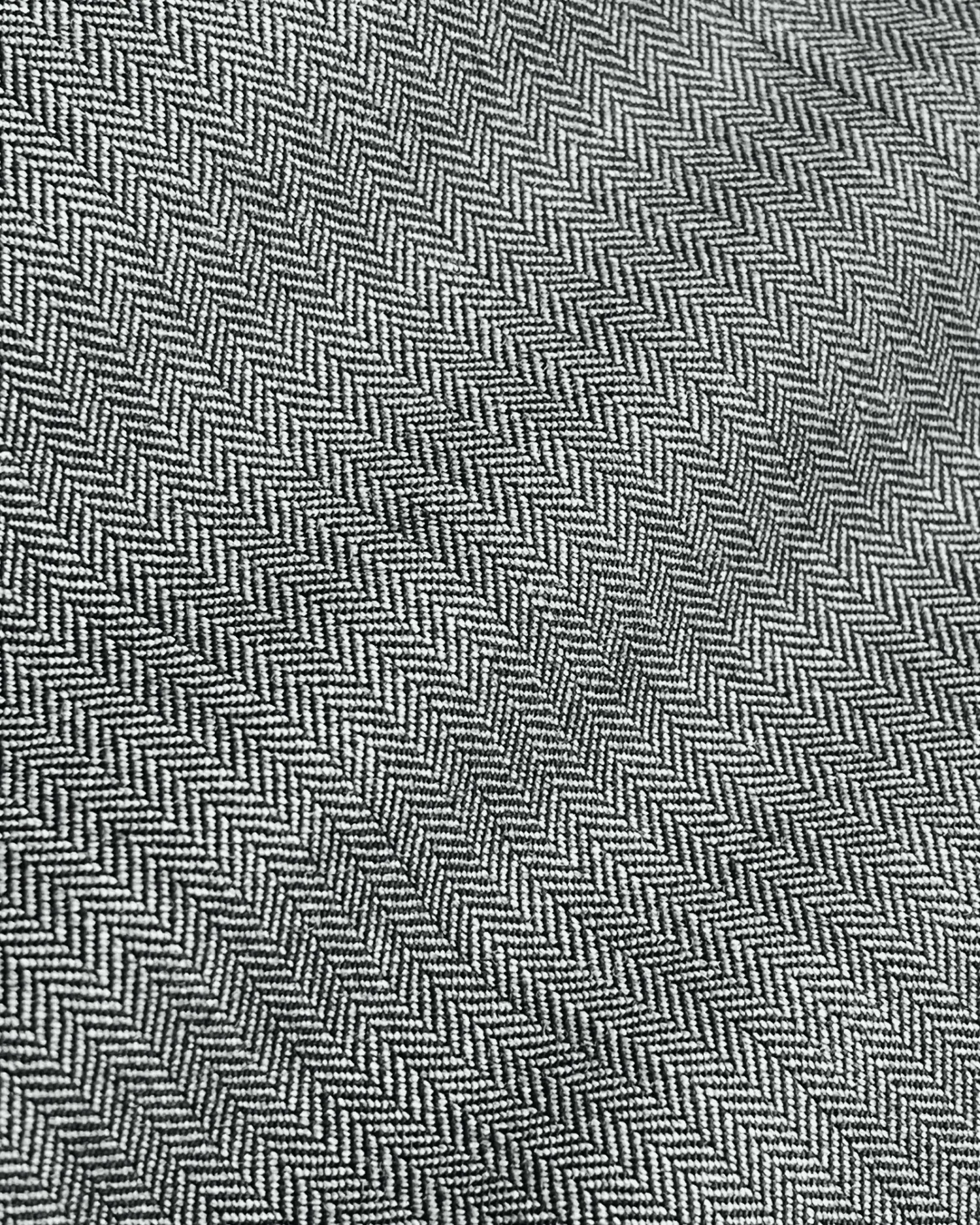 Gray herringbone fabric texture with zigzag pattern, ideal for tailoring and design inspiration.