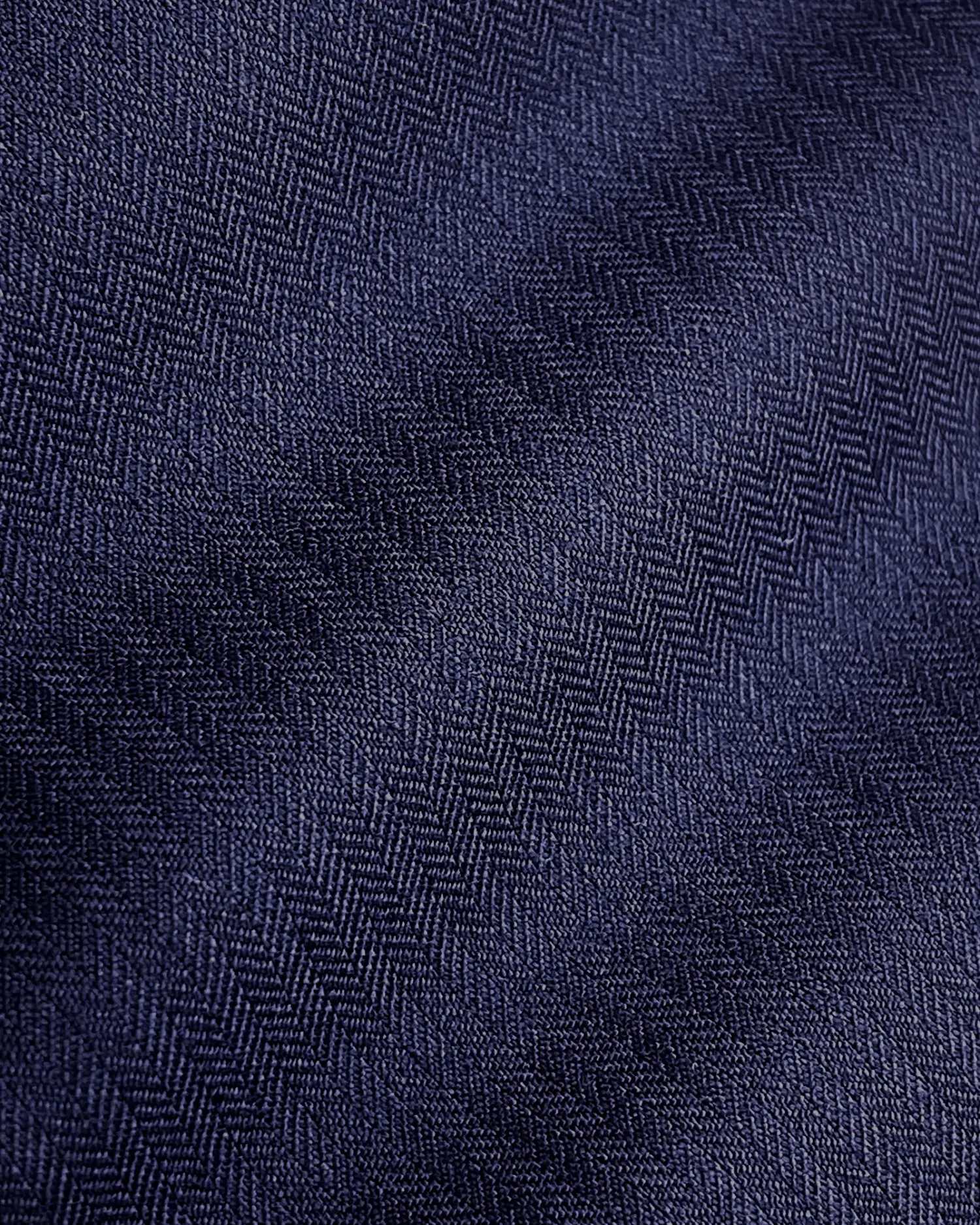 Close-up of a dark blue herringbone fabric texture, showing detailed pattern and weave.