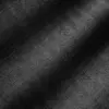 Close-up of black herringbone fabric with detailed zigzag pattern and texture, illuminated by subtle lighting.