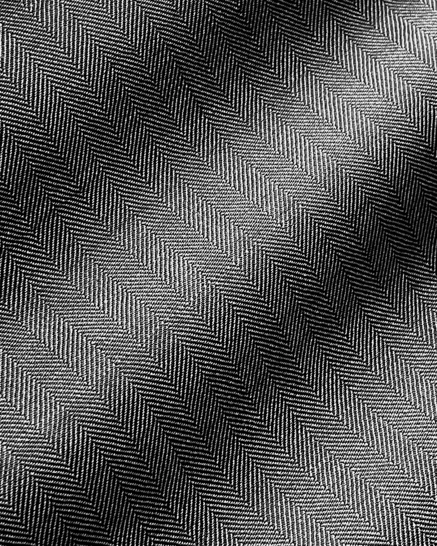 Close-up of black and white herringbone fabric texture with diagonal zigzag pattern.