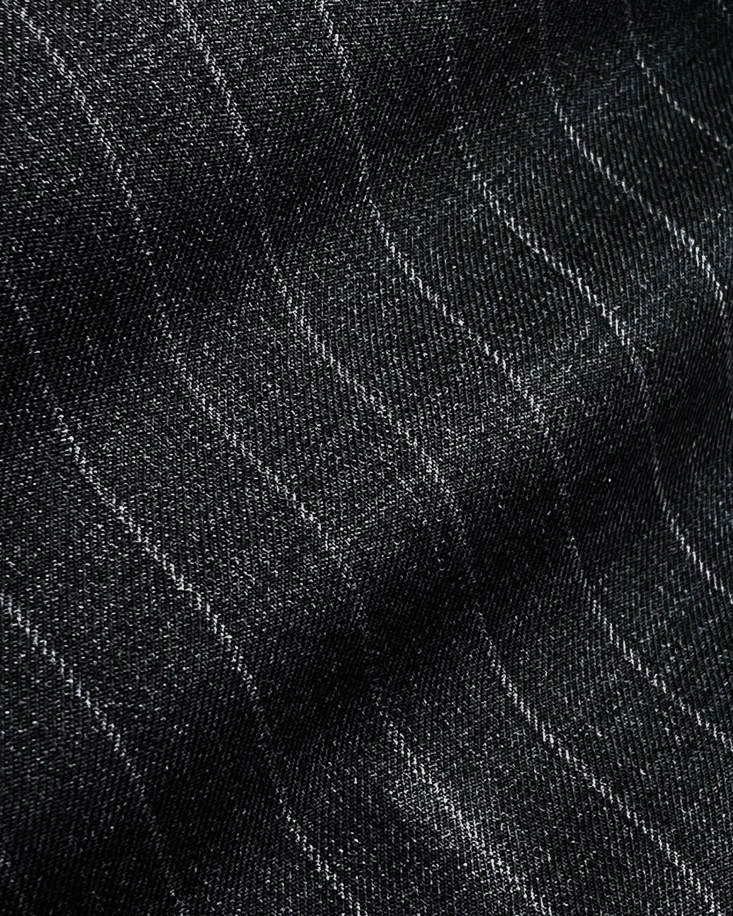 Close-up of dark fabric with subtle vertical pinstripes, showing texture details and pattern.