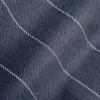 Close-up of dark denim fabric with white stitching creating a wavy pattern.