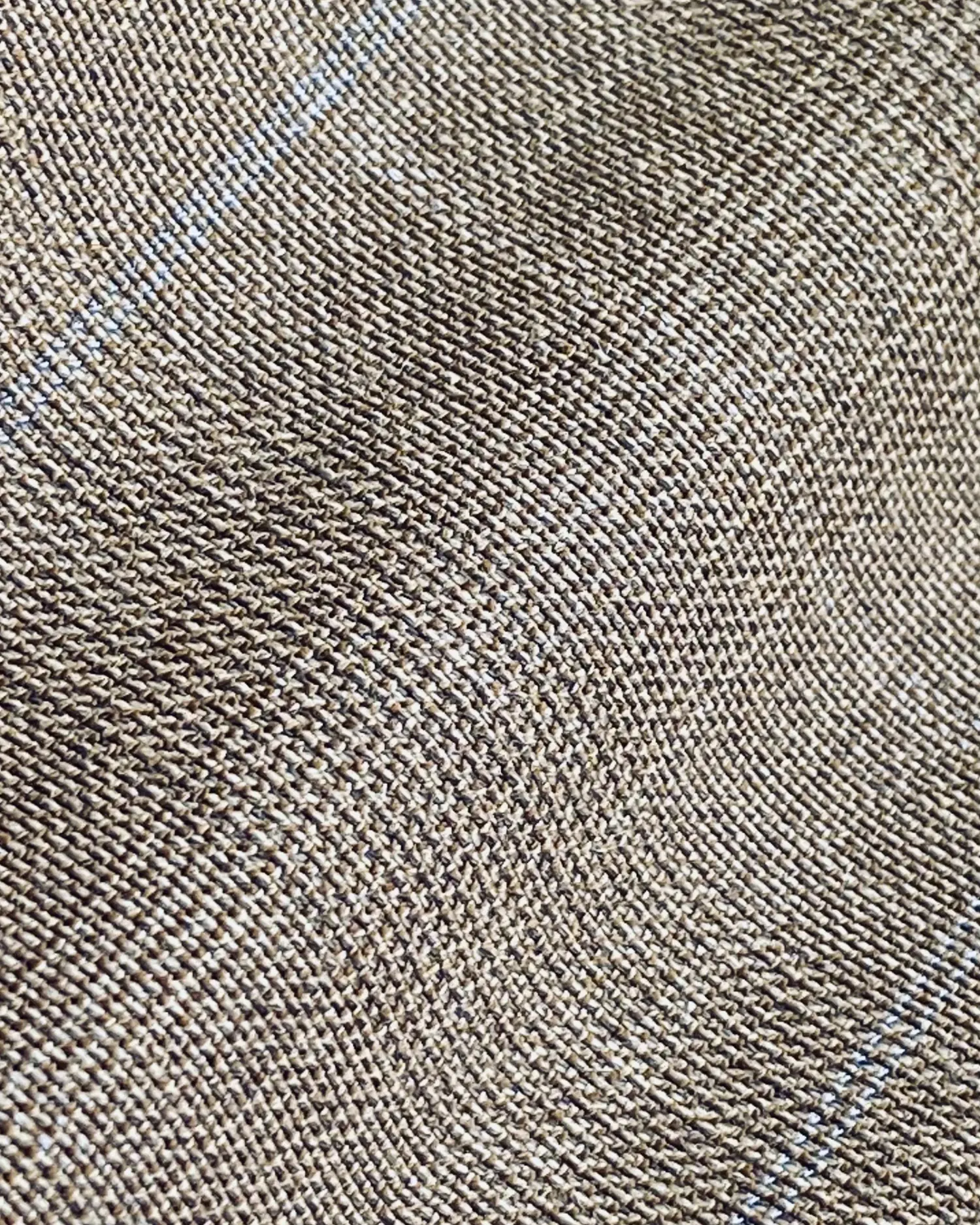 Close-up of a textured brown fabric with a subtle diagonal pattern and fine blue lines.