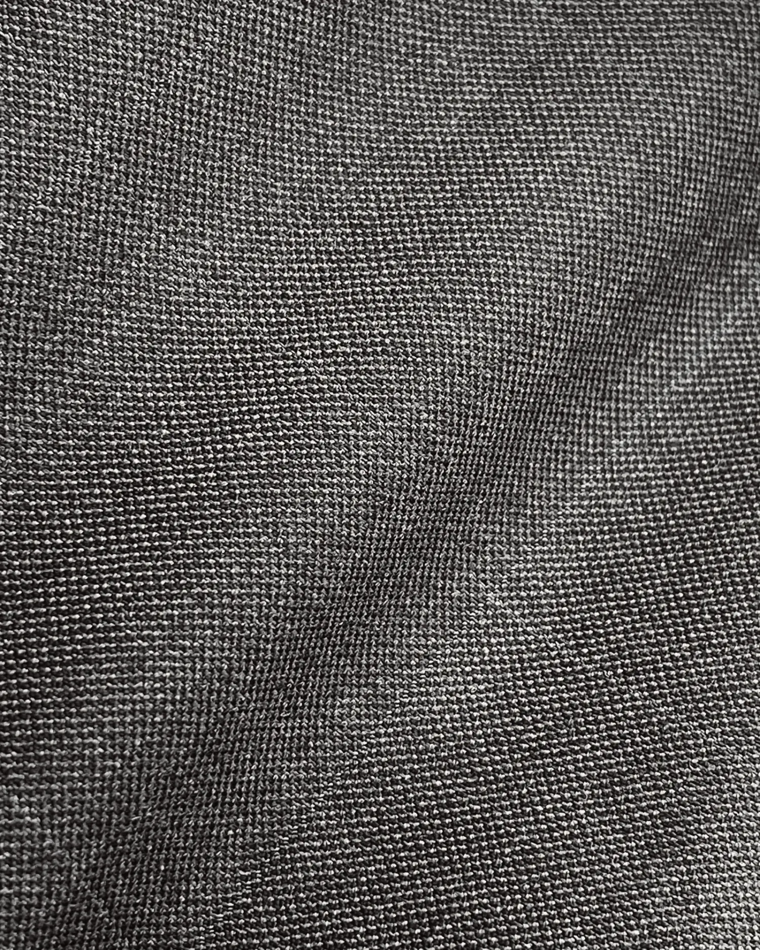 Close-up of a textured dark fabric with a subtle sheen, showing detailed weave pattern. Ideal for clothing or upholstery.