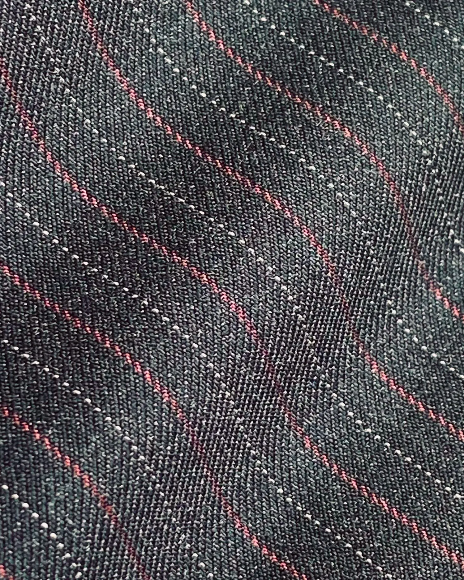 Close-up of dark fabric with wavy red and white stripes, showcasing texture and pattern detail.
