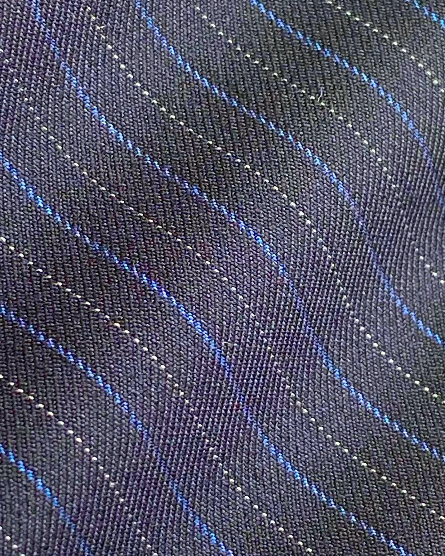 Close-up of a textured fabric with wavy blue and gray lines, highlighting detail and pattern.