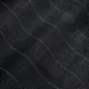 Close-up of textured black fabric with subtle curved lines, showcasing intricate stitching and pattern detail.