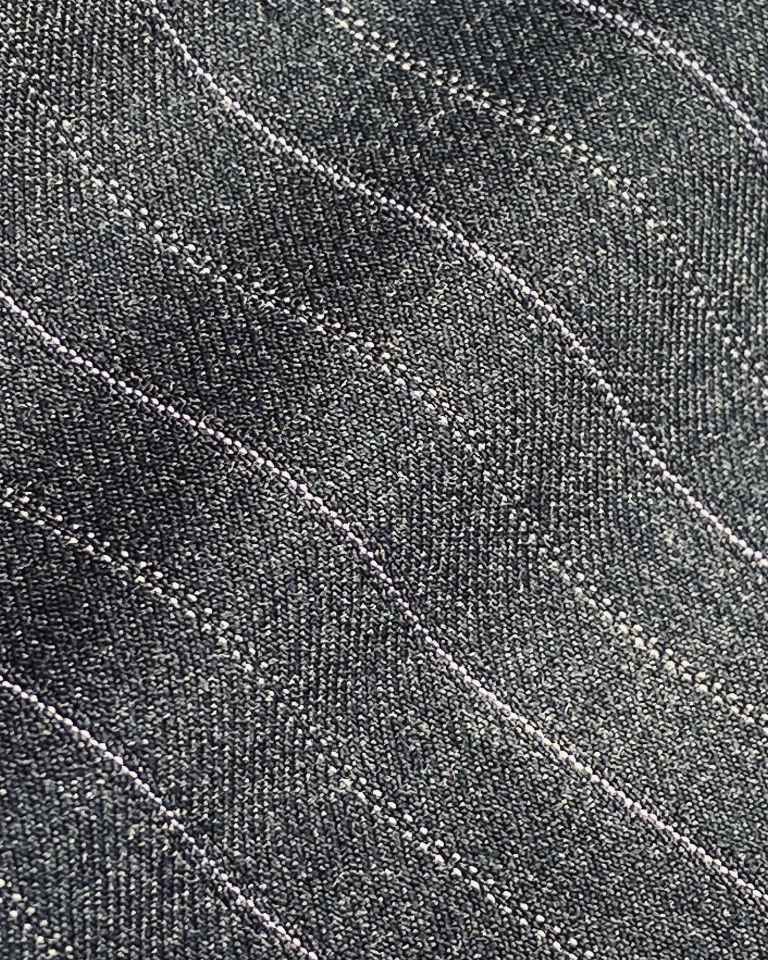 Close-up of textured denim fabric with wavy stitching details, showcasing intricate woven pattern.