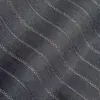 Close-up of dark fabric with wavy stitch pattern, showcasing detailed textile texture and design.