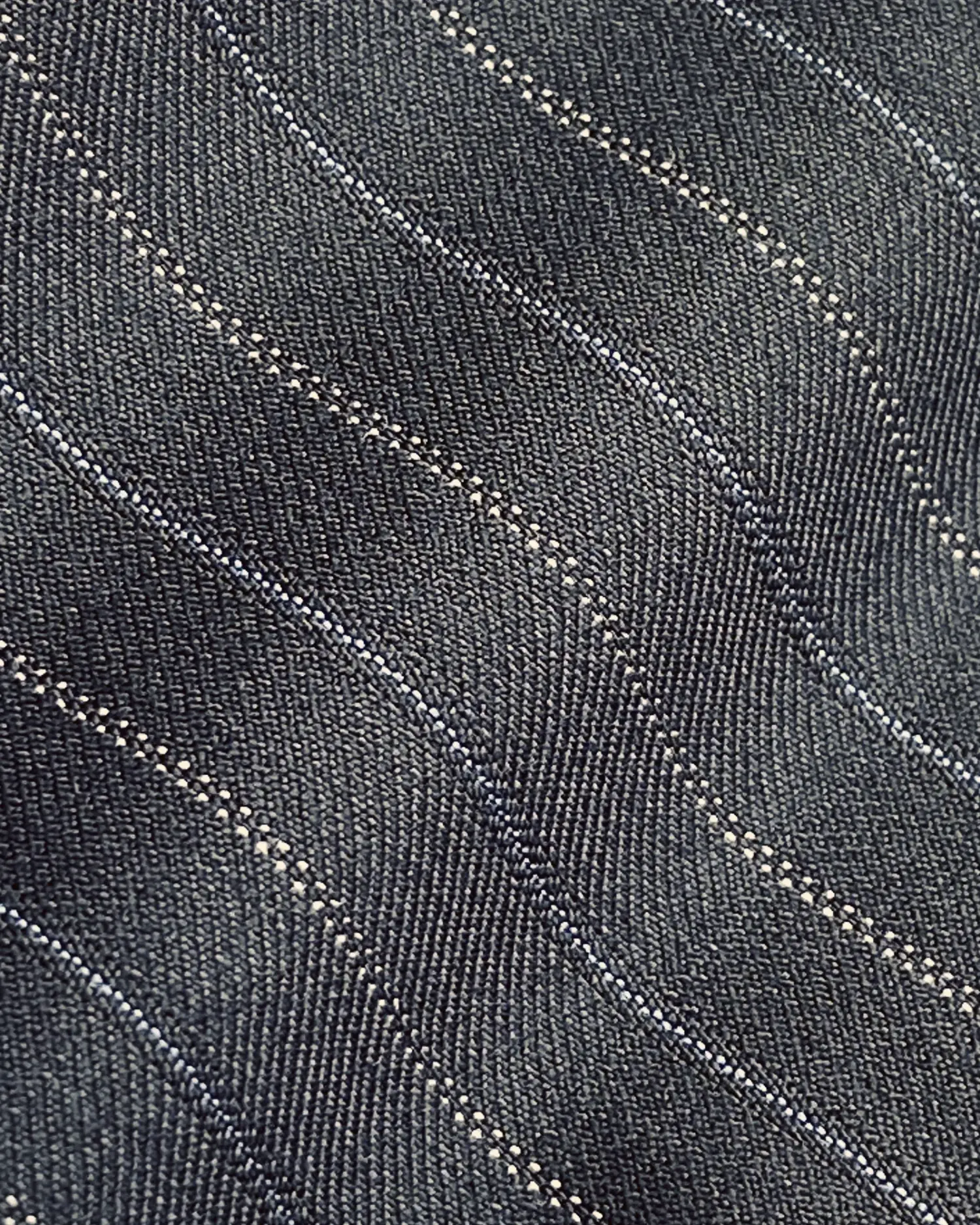 Close-up of dark fabric with wavy stitch pattern, showcasing detailed textile texture and design.