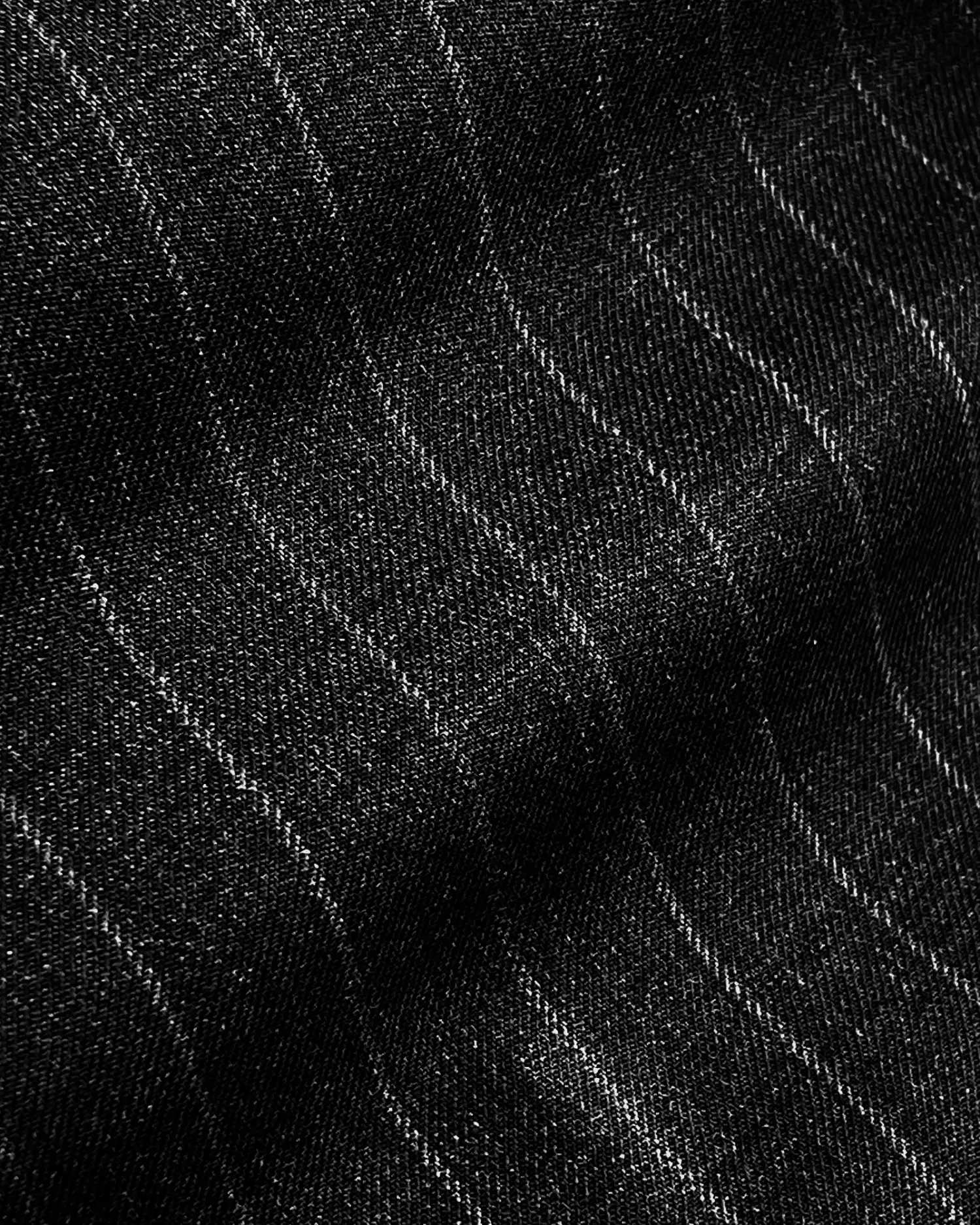 Close-up of black denim fabric with subtle striped pattern, showcasing texture and detail.