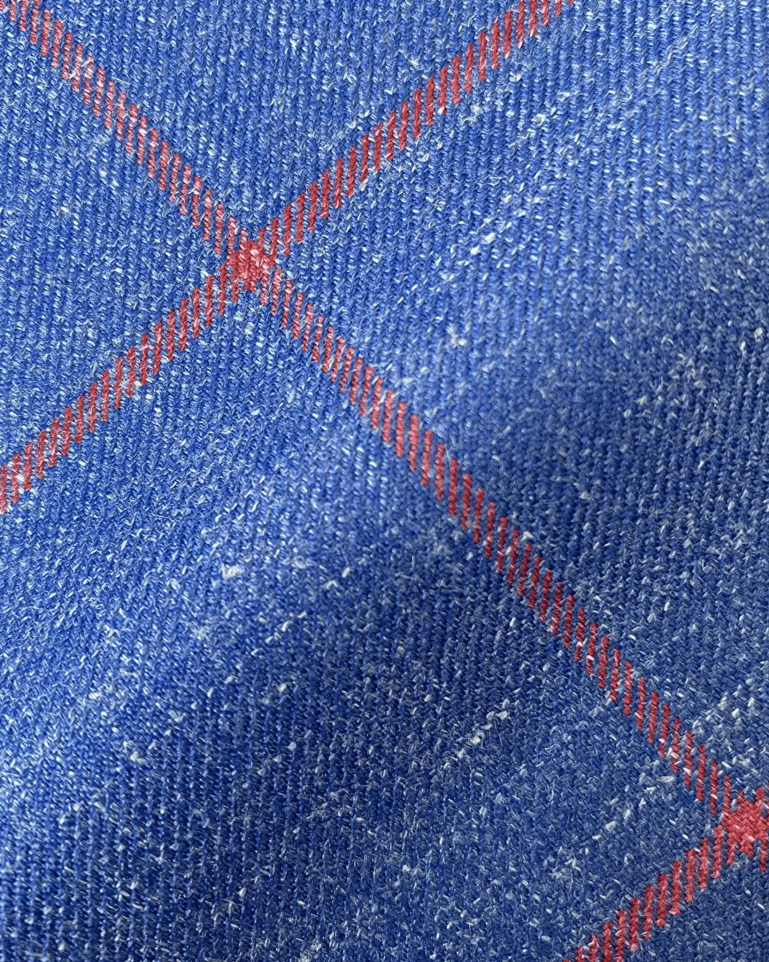 Close-up of blue fabric with red diagonal plaid pattern, highlighting texture and design details.