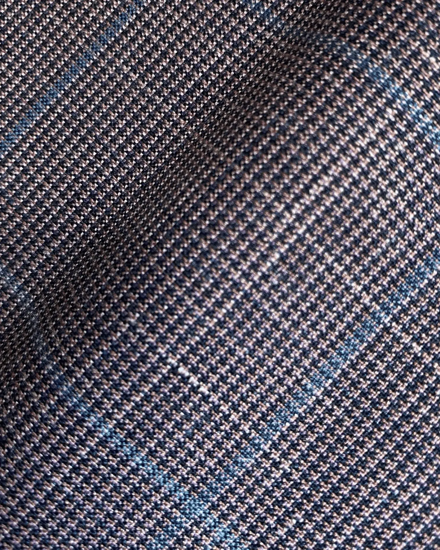 Close-up of textured fabric with a blue check pattern, highlighting detailed weaving suitable for tailoring.