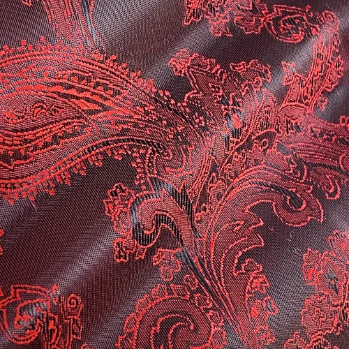 Close-up of intricate red and black paisley fabric pattern with swirling details.