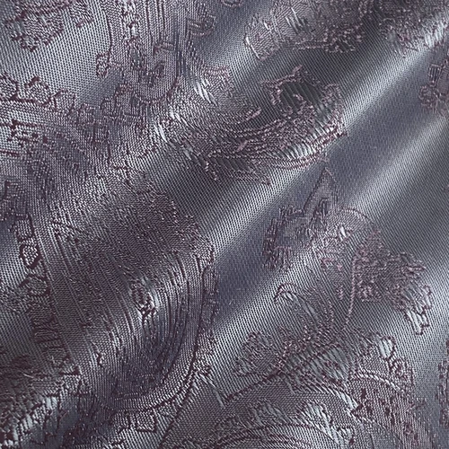 Silver paisley jacquard fabric with intricate patterns and glossy texture, ideal for elegant upholstery and fashion design.