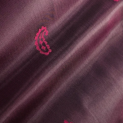 Close-up of purple and maroon fabric with a subtle paisley pattern design, highlighting texture and fine details.